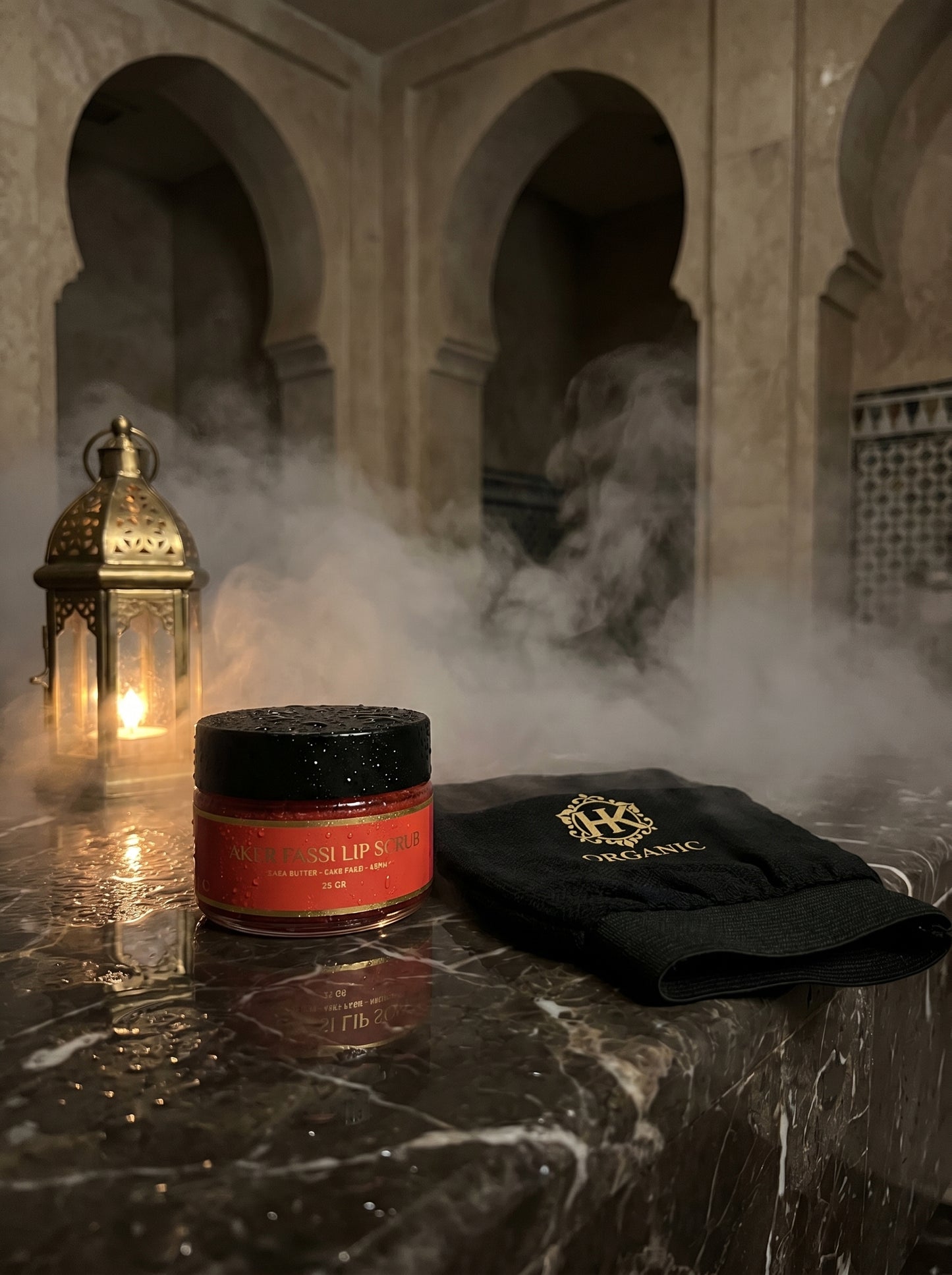 Jar of lip balm and black towel on a marble surface with a lantern and smoke in the background