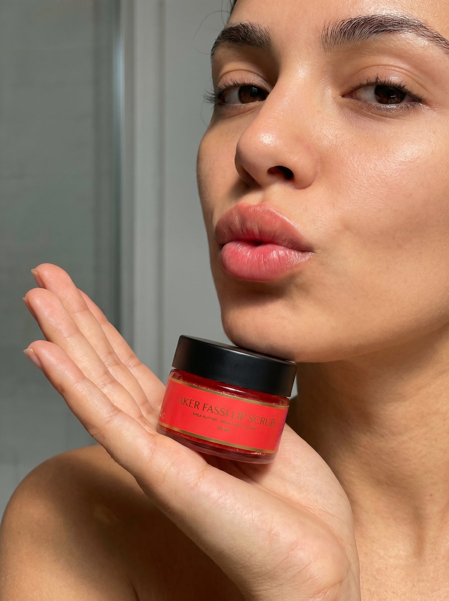 Woman holding a red jar of cream close to her face