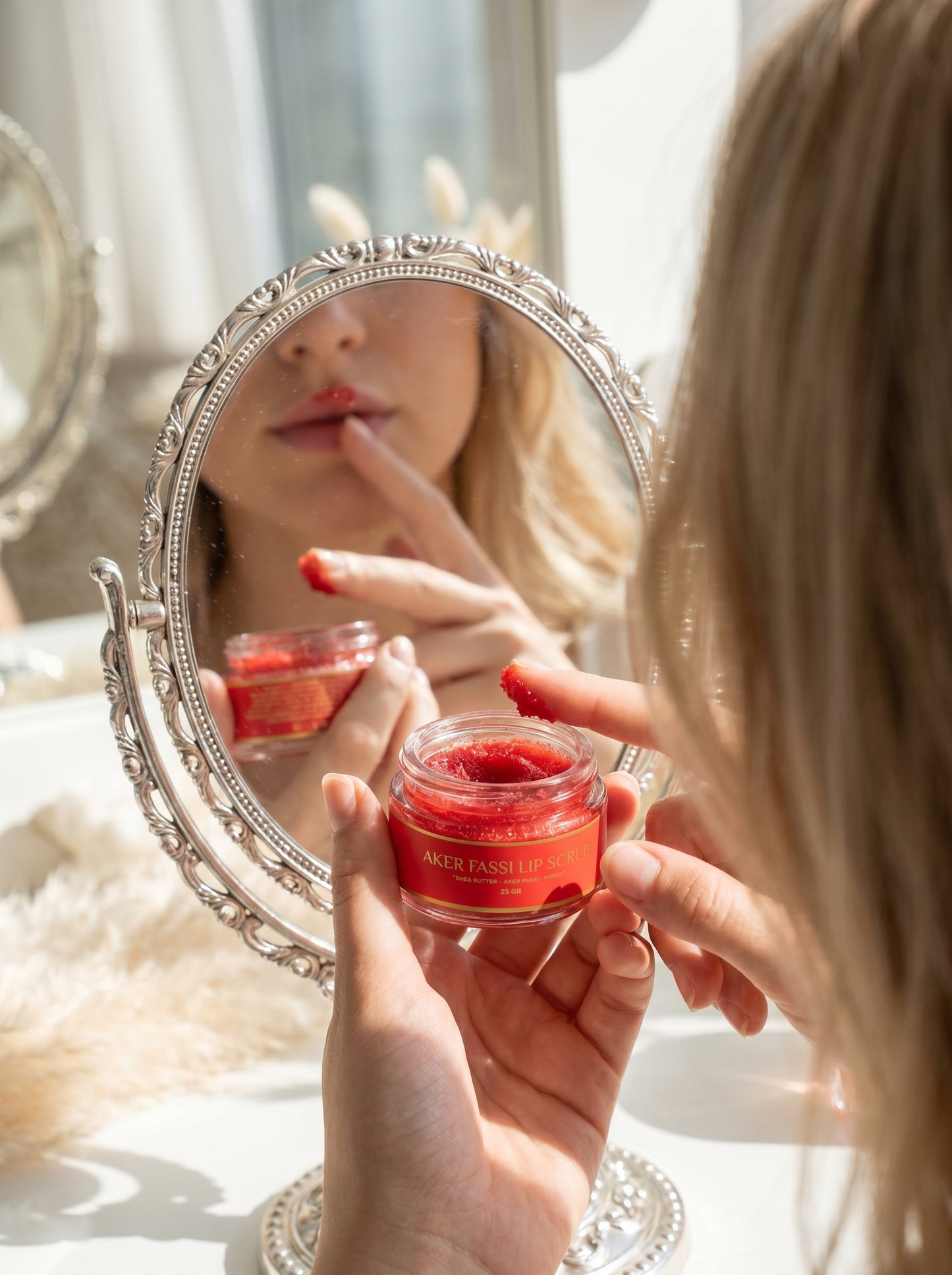 Person applying a red lip balm in front of a mirror