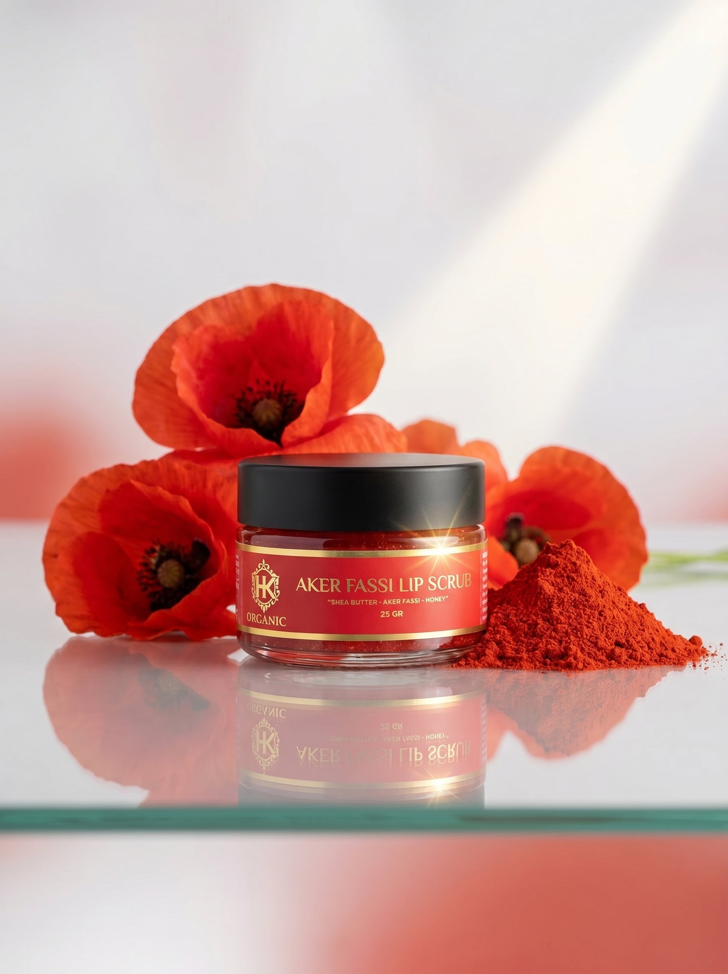 Jar of Aker Fassi lip scrub with red poppies on a reflective surface