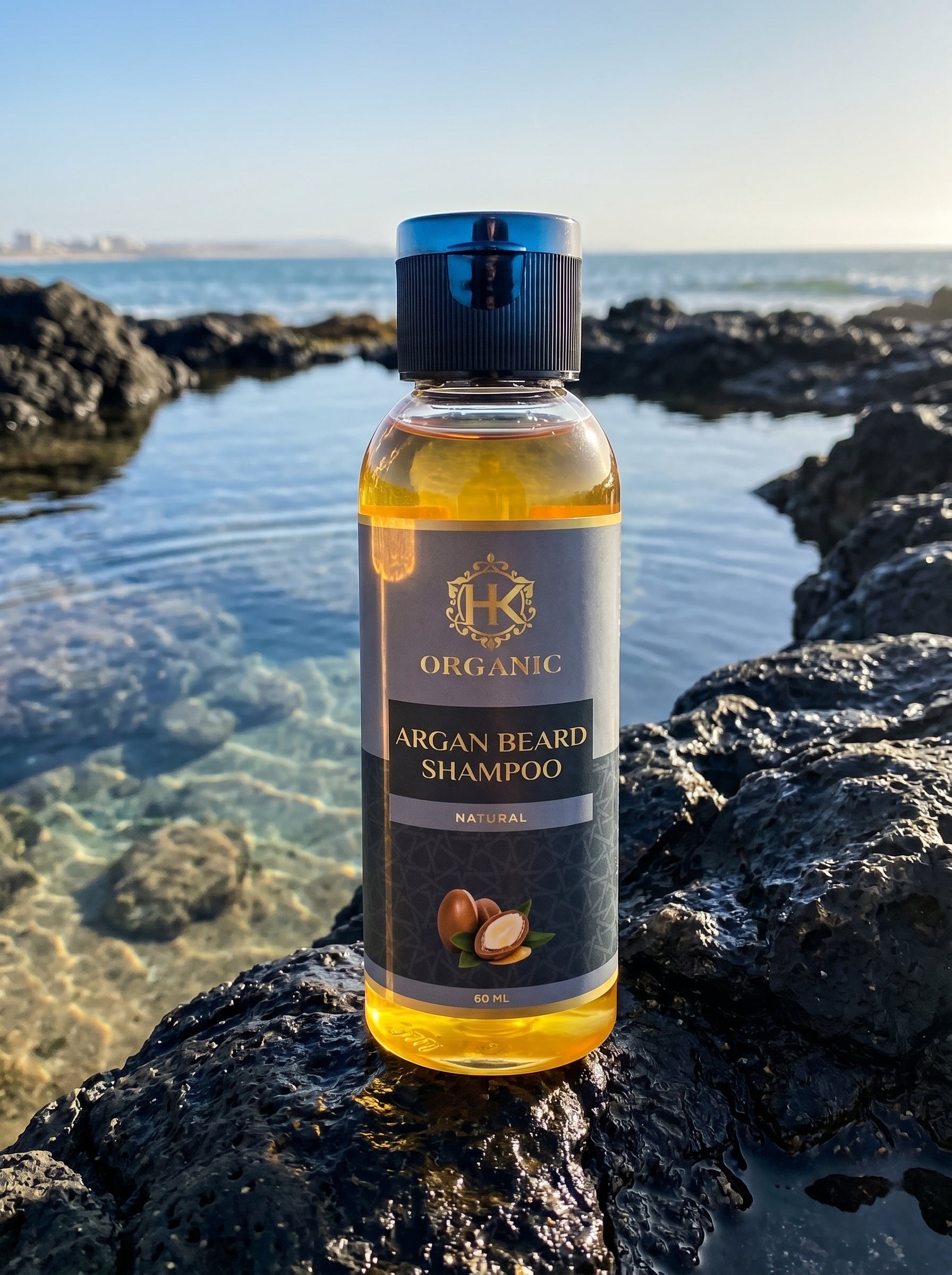 Bottle of Organic Argan Beard Shampoo on a rocky beach with ocean view