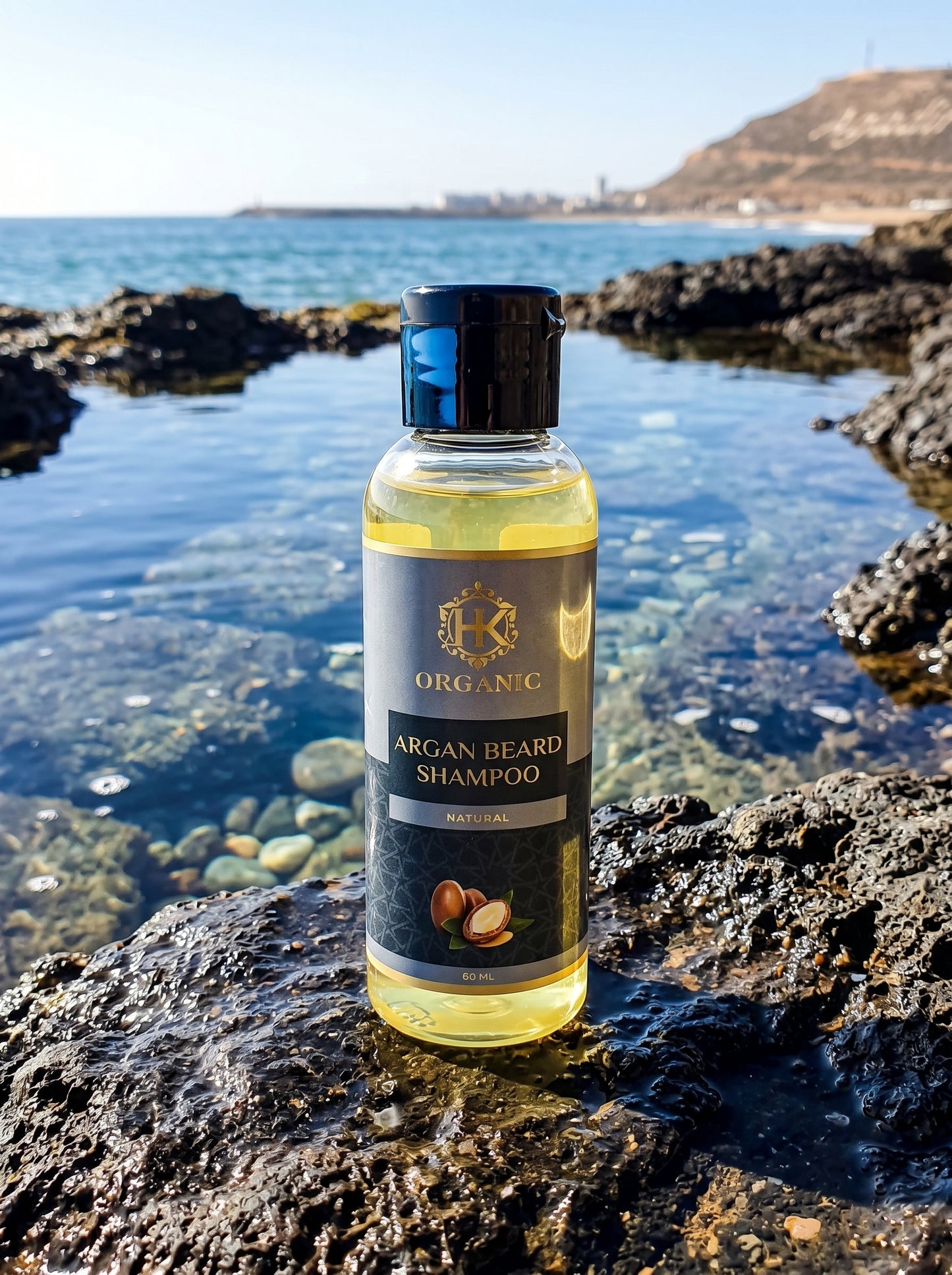 Bottle of Organic Argan Beard Shampoo on a rocky shoreline with water in the background