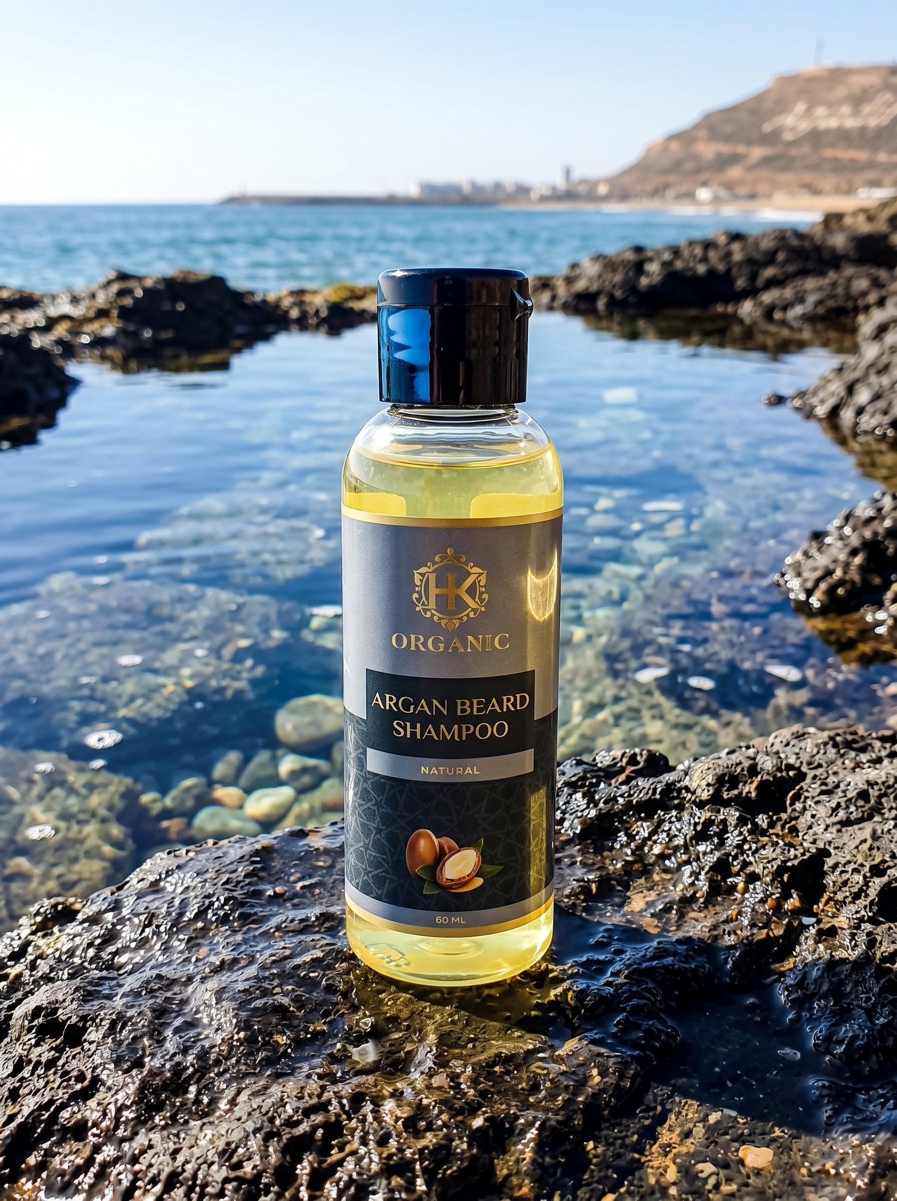 Bottle of Organic Argan Beard Shampoo on a rocky shoreline with water in the background