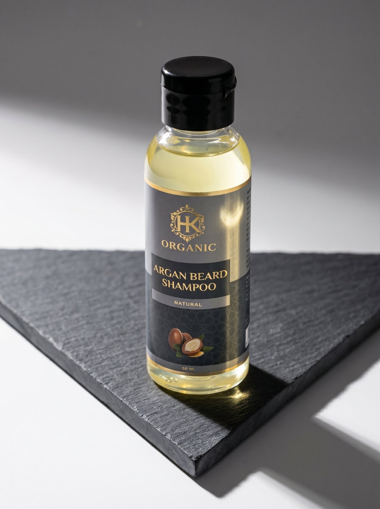 Bottle of organic argan beard shampoo on a dark surface with a gray background