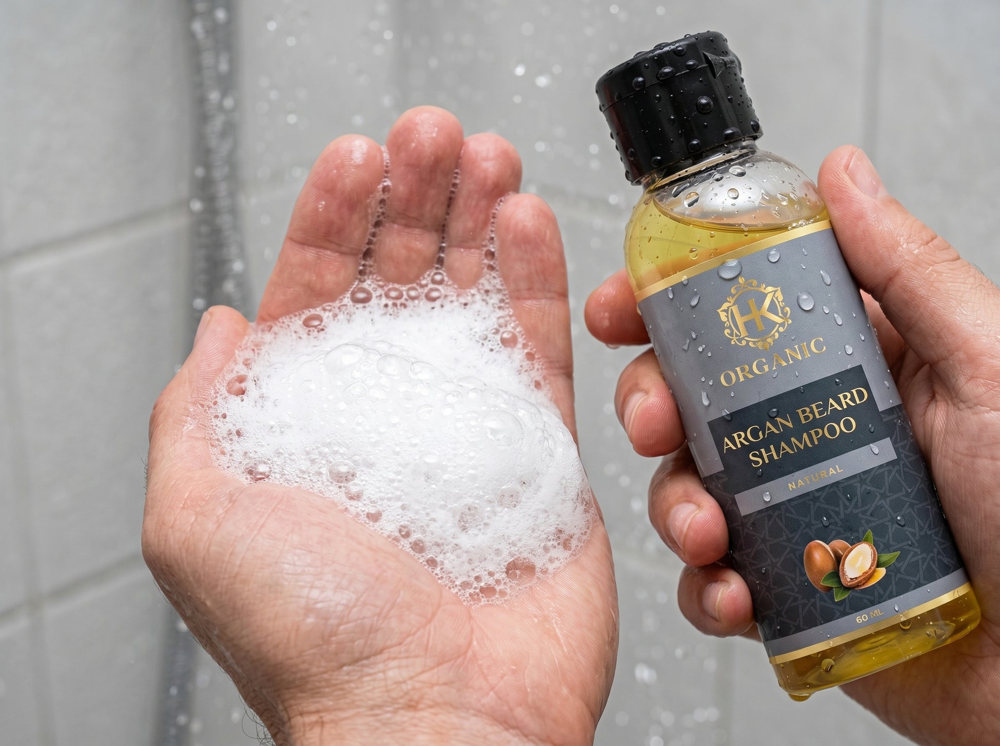 Bottle of organic argan beard shampoo with a hand holding foamy soap.