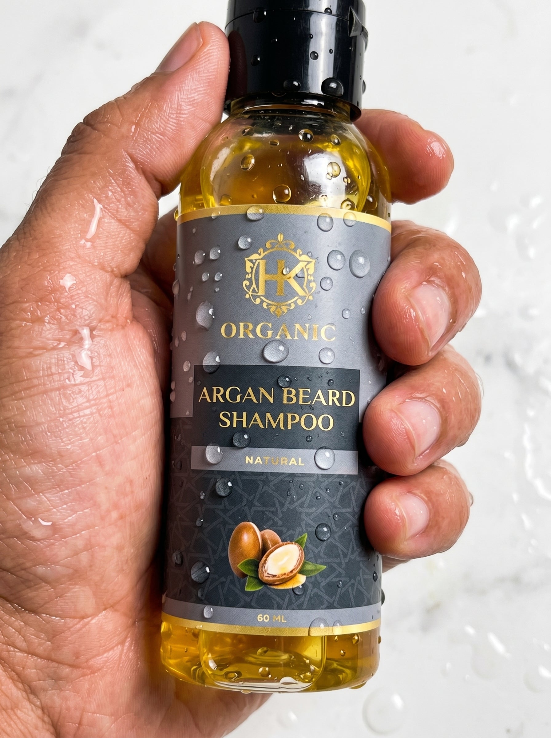 Hand holding a bottle of organic argan beard shampoo with a visible brand logo.
