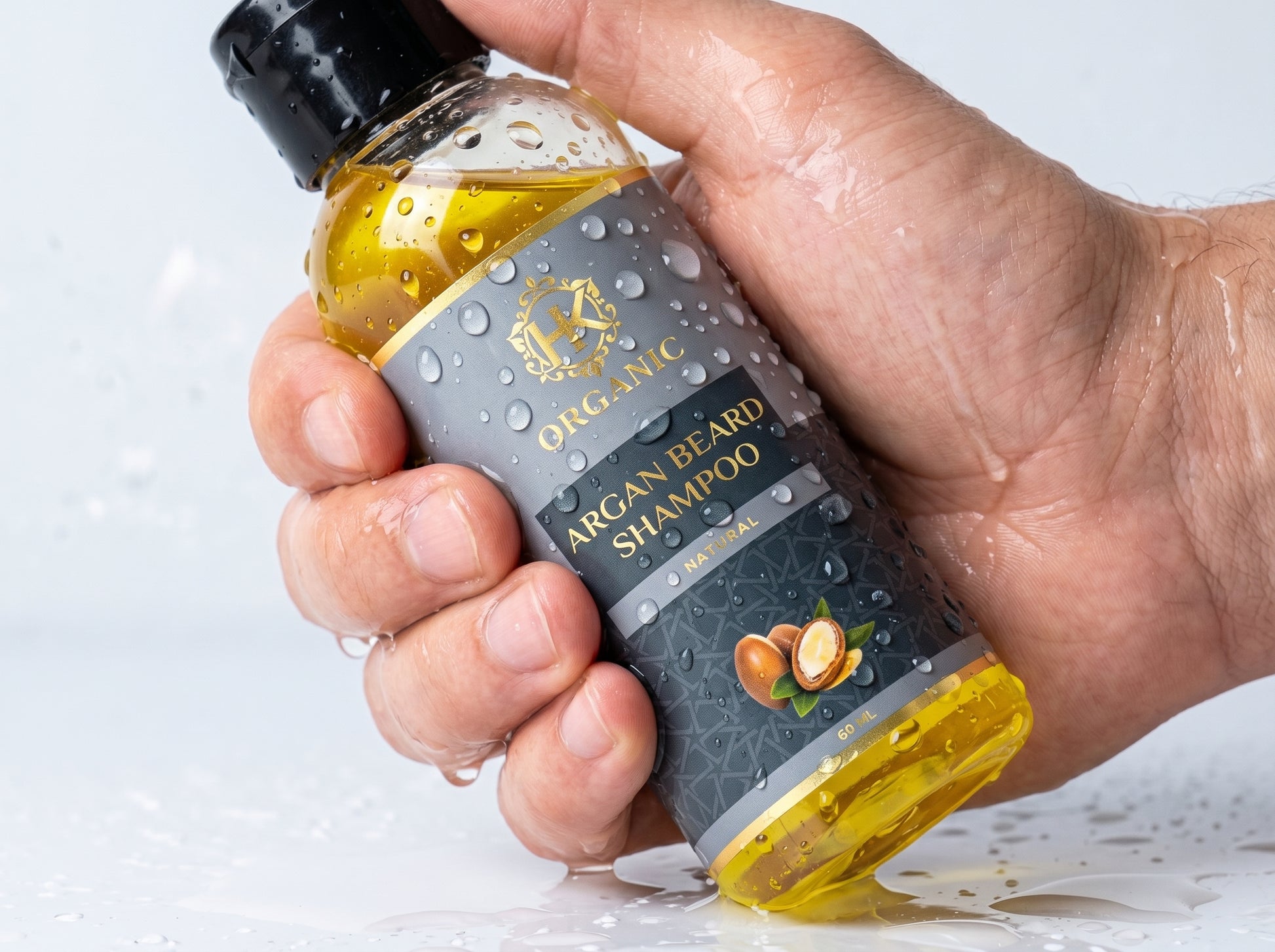 Hand holding a bottle of Organic Argan Beard Shampoo with a visible brand logo.