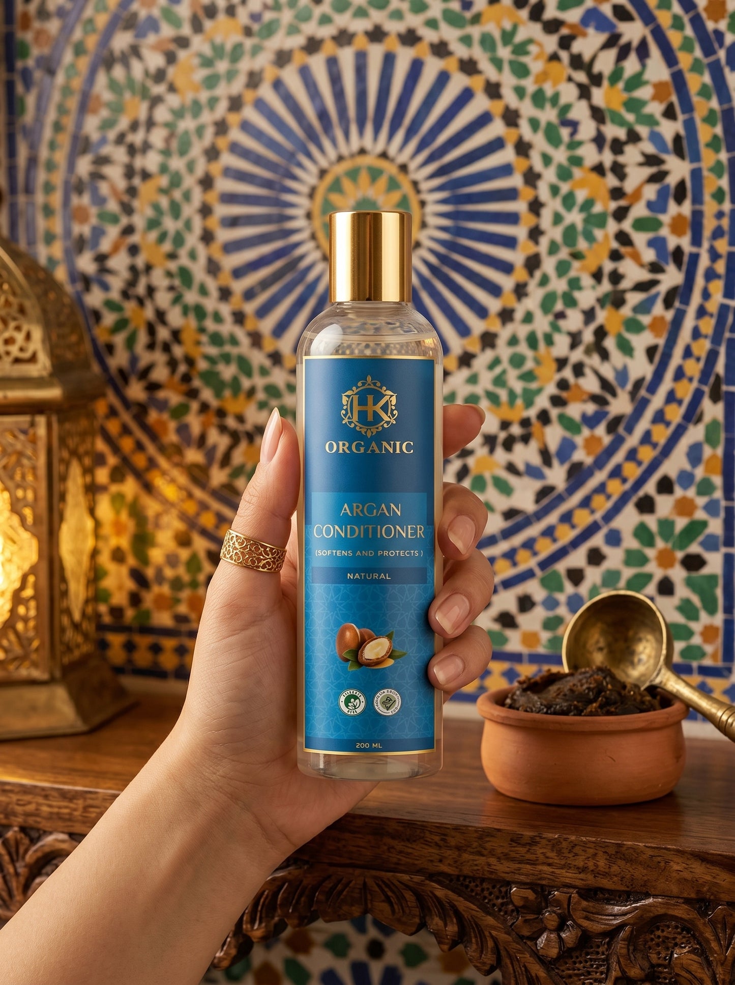 Hand holding a bottle of Organic Argan Conditioner against a decorative background