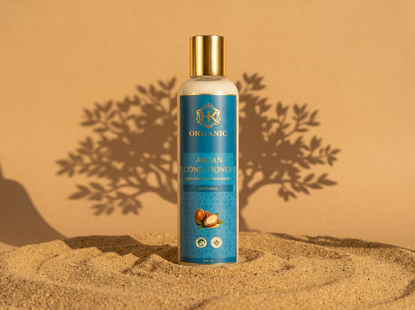 Bottle of organic argan conditioner on a sandy background with a tree shadow.