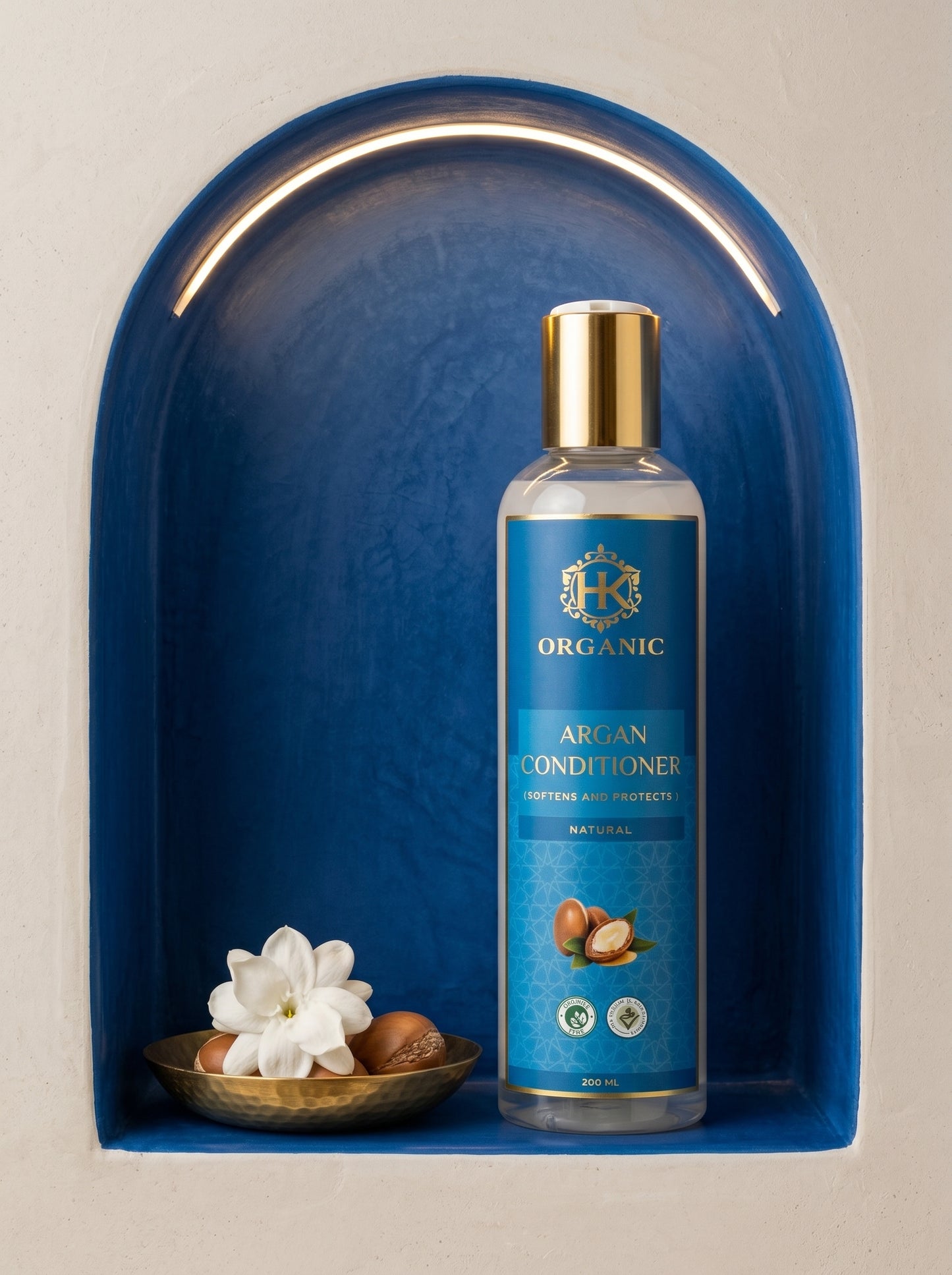 Bottle of organic argan conditioner on a blue shelf with flowers and nuts.