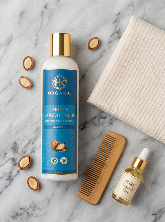 Organic argan conditioner bottle with argan oil, comb, and nuts on a marble background