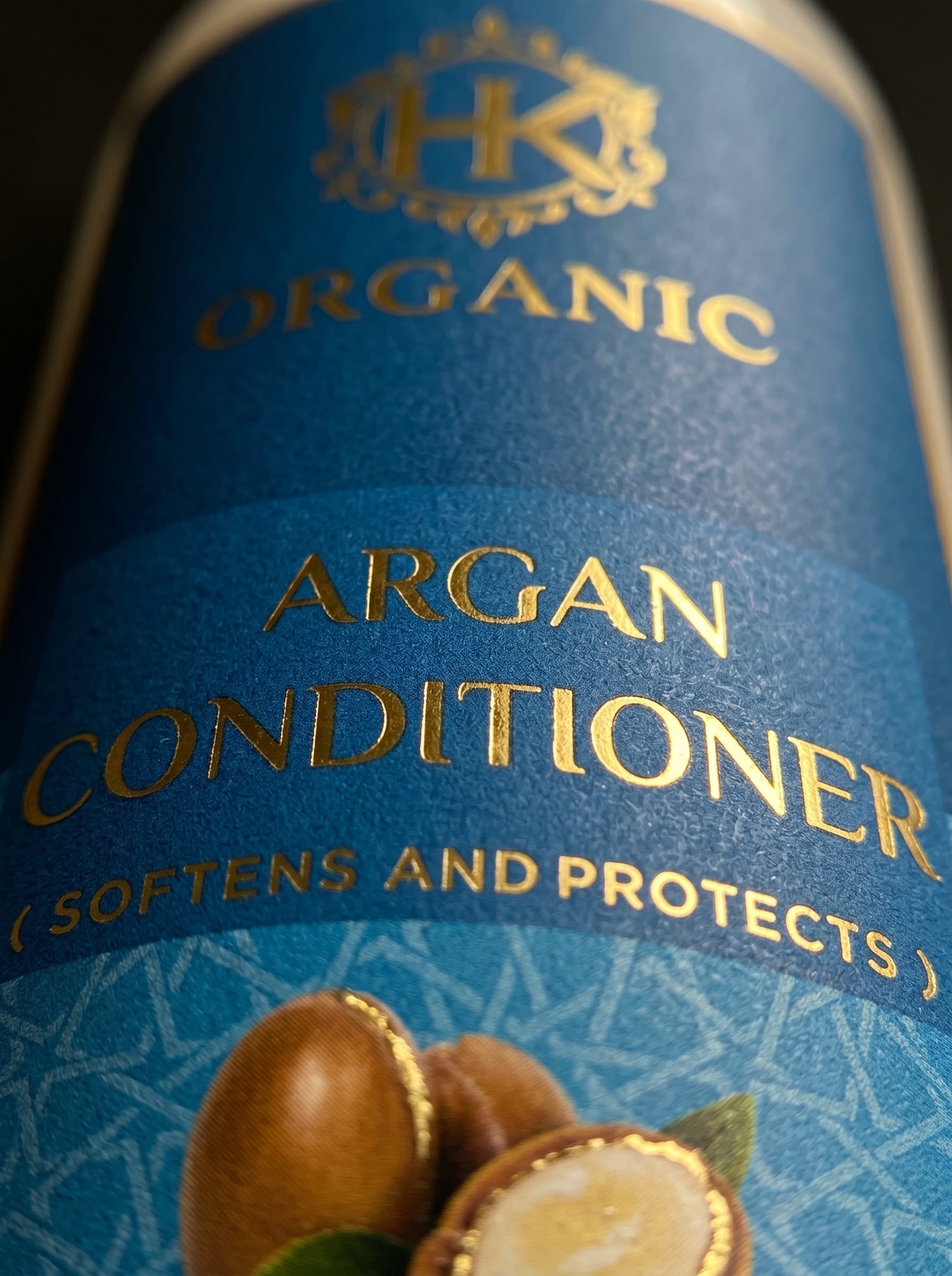 Close-up of a bottle label for organic argan conditioner with gold text on a blue background.