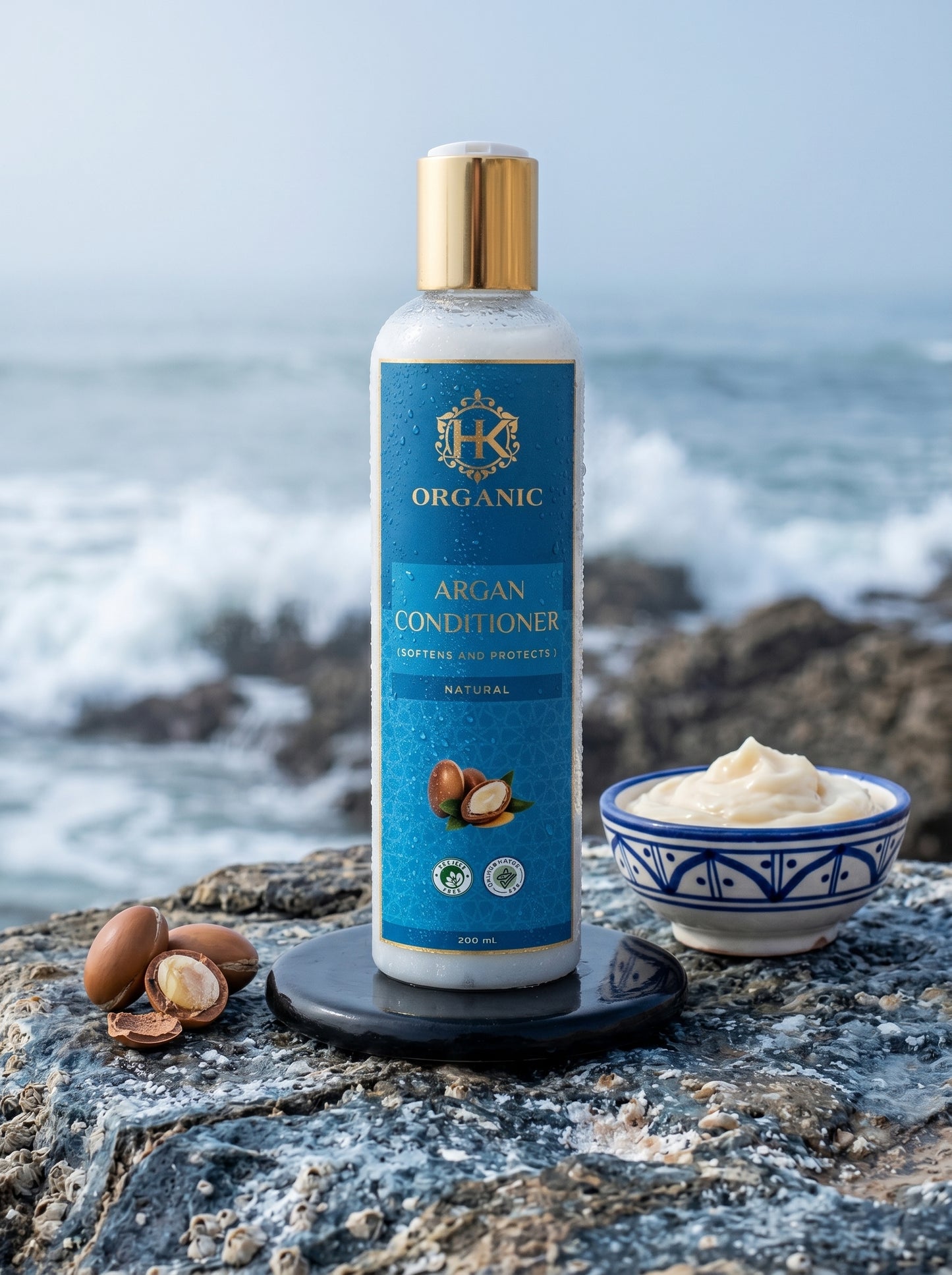 Bottle of organic argan conditioner with ingredients on a rocky beach.
