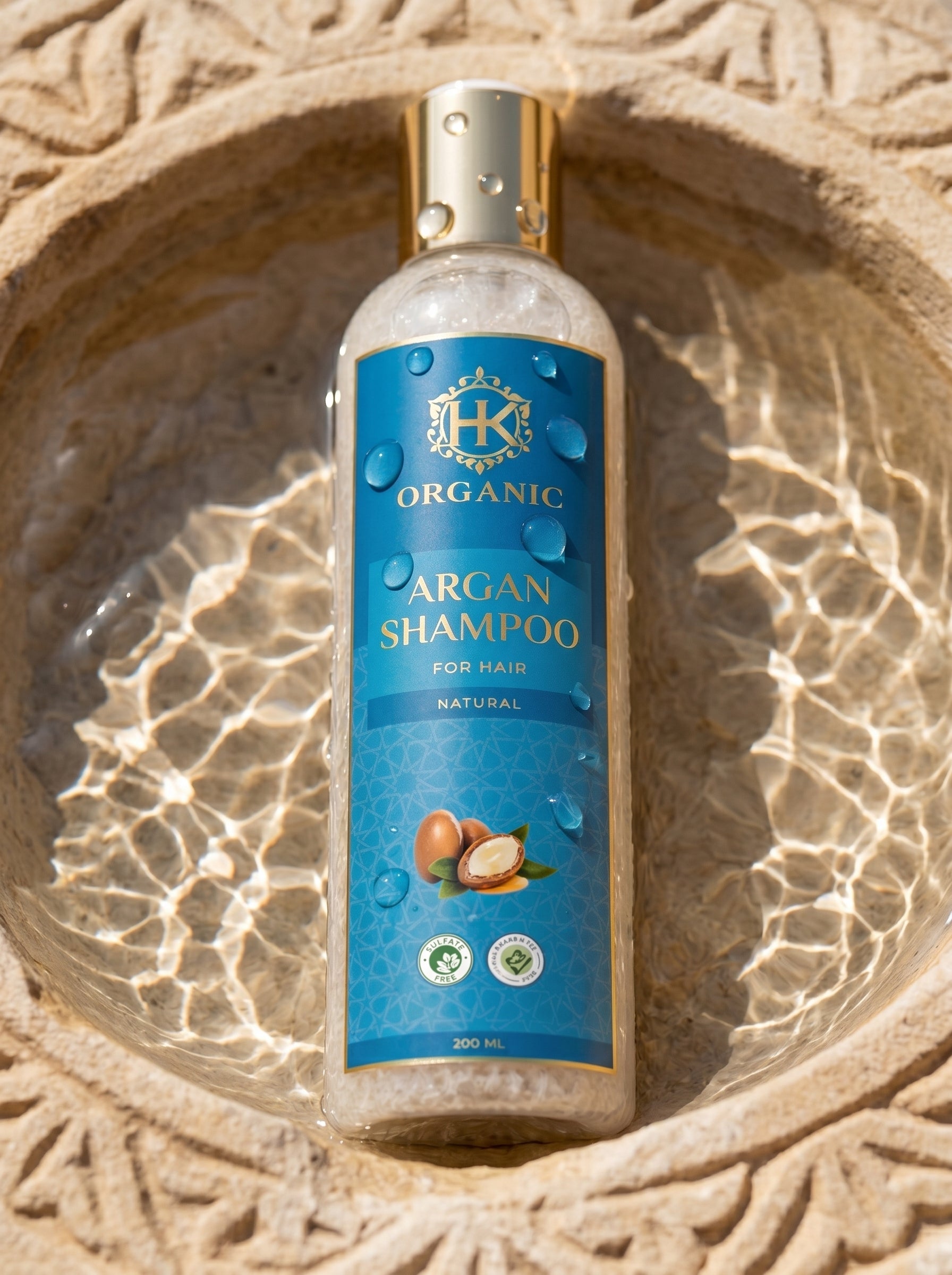 Organic Argan Shampoo bottle with blue label on a textured stone background