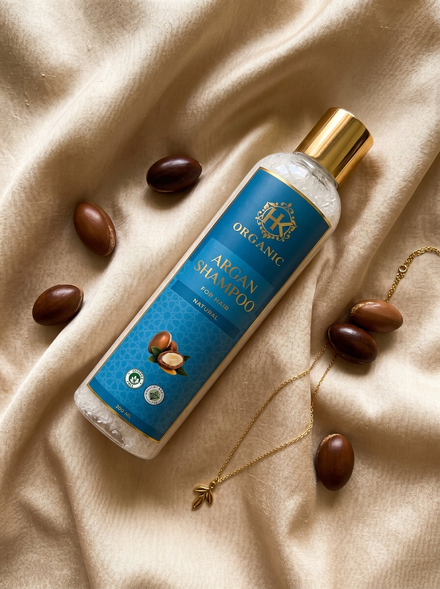 Bottle of Organic Argan Shampoo with argan seeds on a beige fabric background