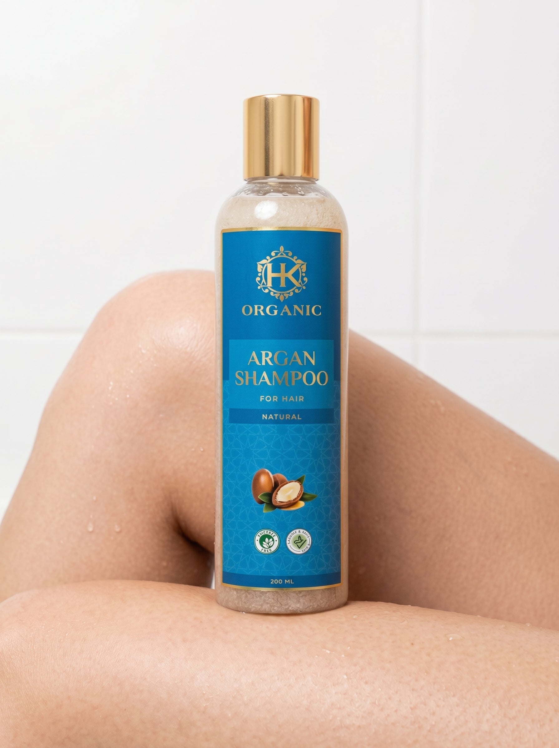 Bottle of HK Organic Argan Shampoo on a person's leg with a white background