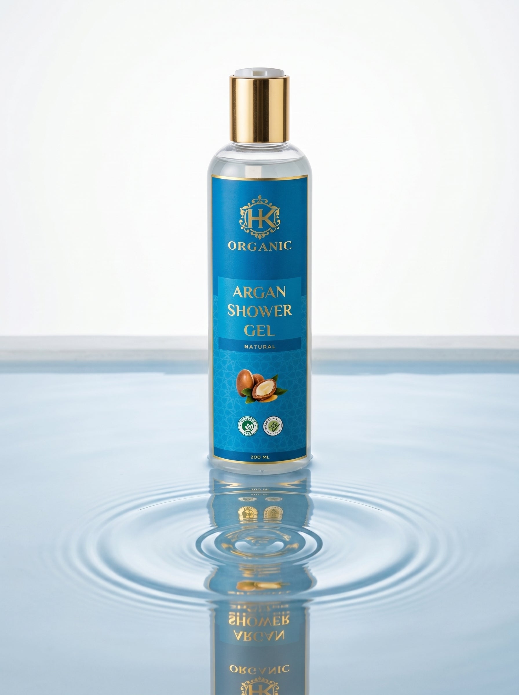 Bottle of organic argan shower gel with a gold cap on a reflective water surface.