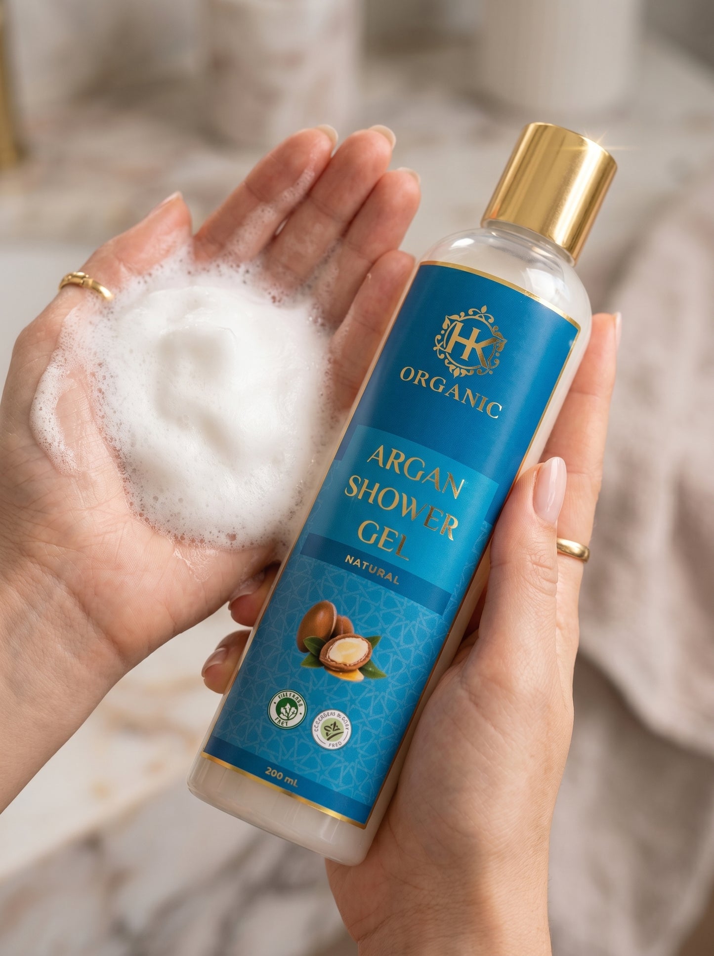 Bottle of Organic Argan Shower Gel held by a hand with soap suds, brand logo visible