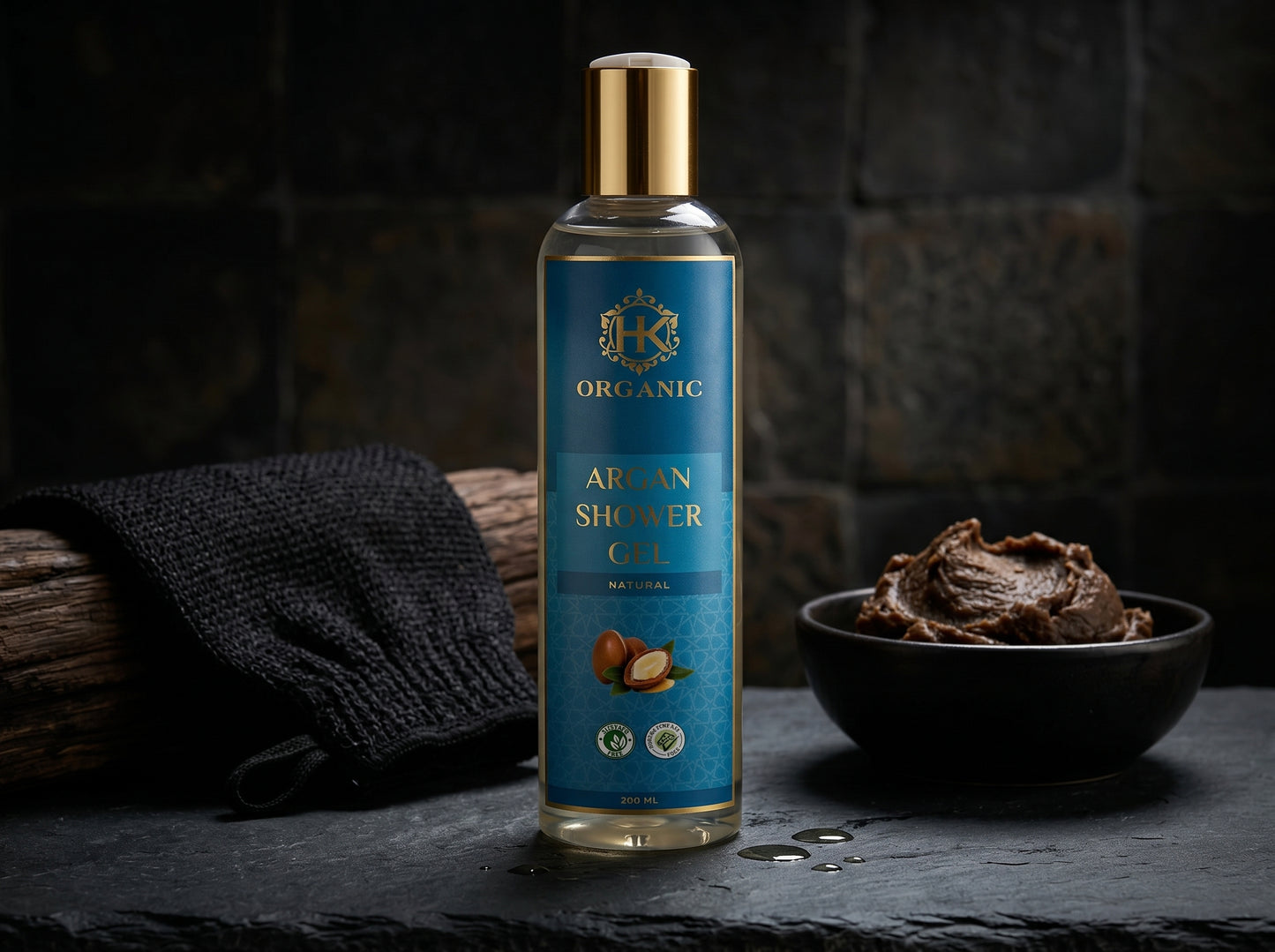 Bottle of organic argan shower oil with a towel and bowl on a dark background