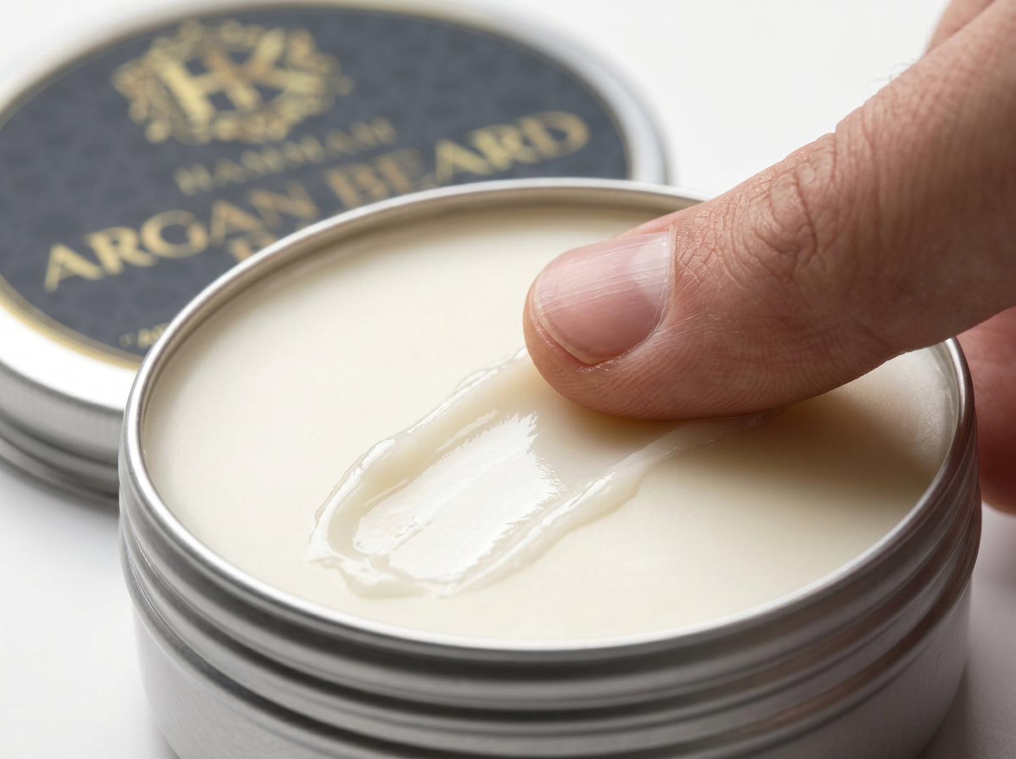 Hand applying cream from a jar with 'Hanskin' branding, on a white background.