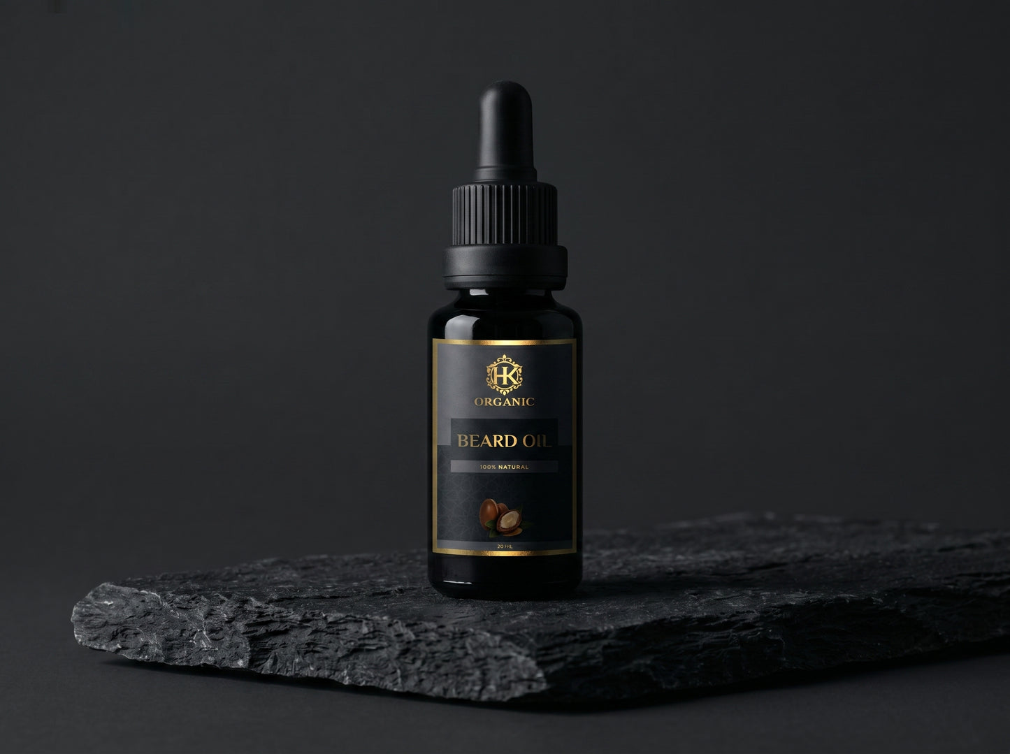 Black bottle of beard oil with a dropper on a dark stone surface against a black background