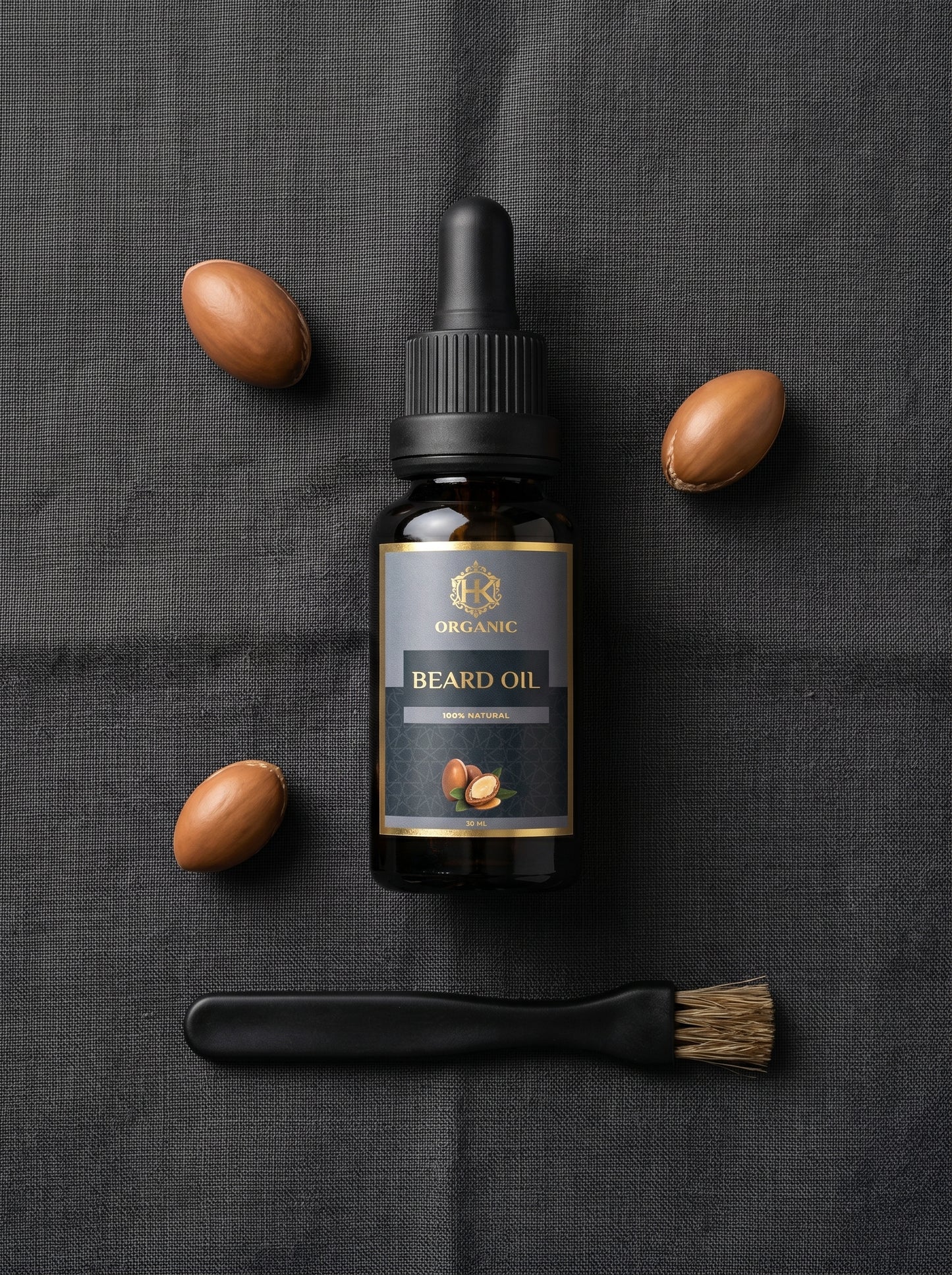Beard oil bottle with almonds and a brush on a dark fabric background