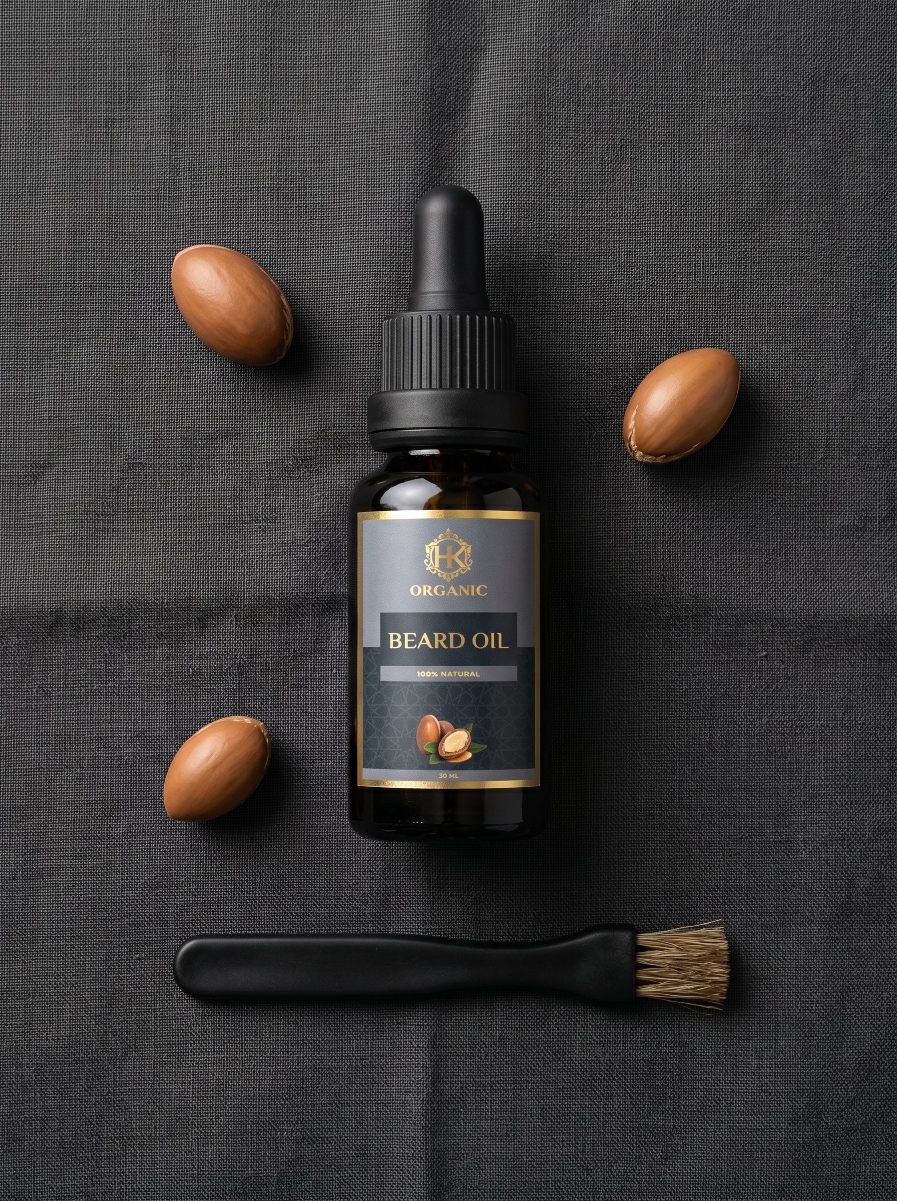 Beard oil bottle with almonds and a brush on a dark fabric background