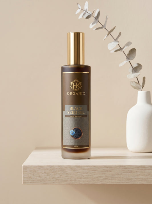 Bottle of Black Seed Oil on a wooden shelf with a white vase and eucalyptus branch.