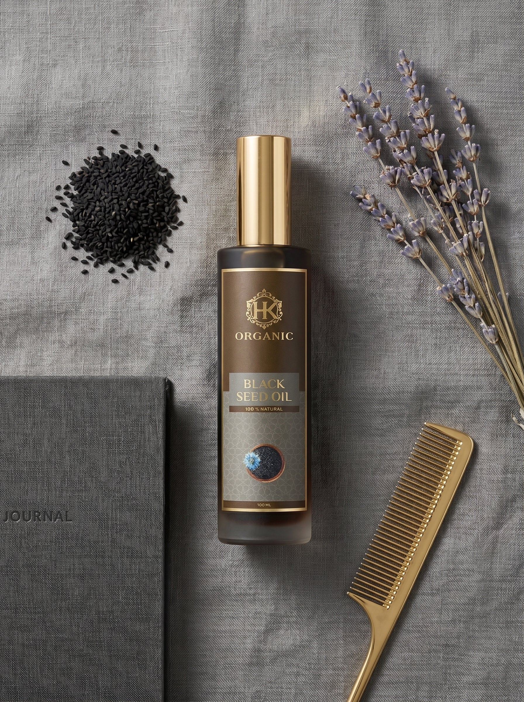 Bottle of organic black seed oil with a comb and lavender on a gray surface