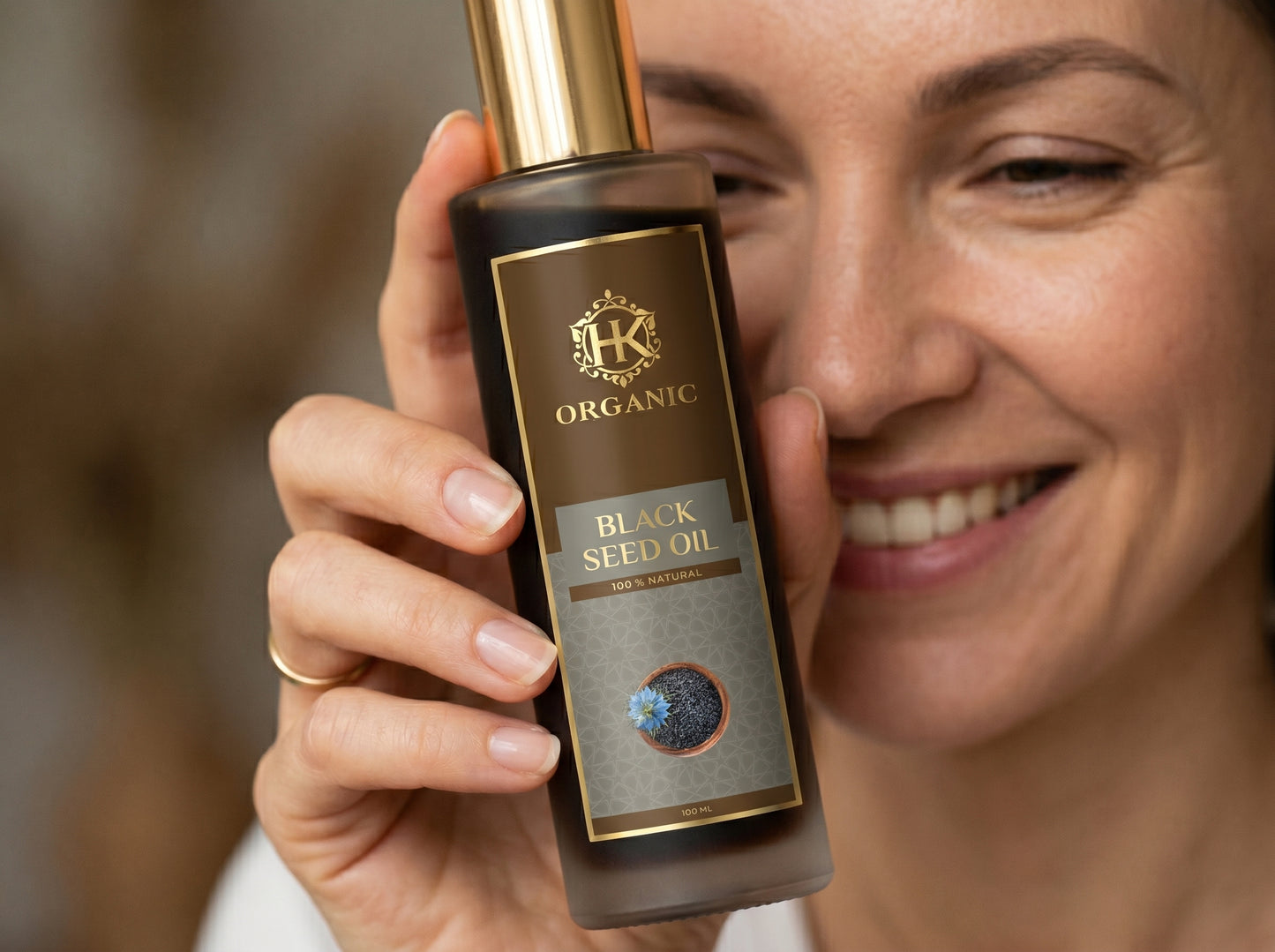 Woman holding a bottle of organic black seed oil with a blurred background