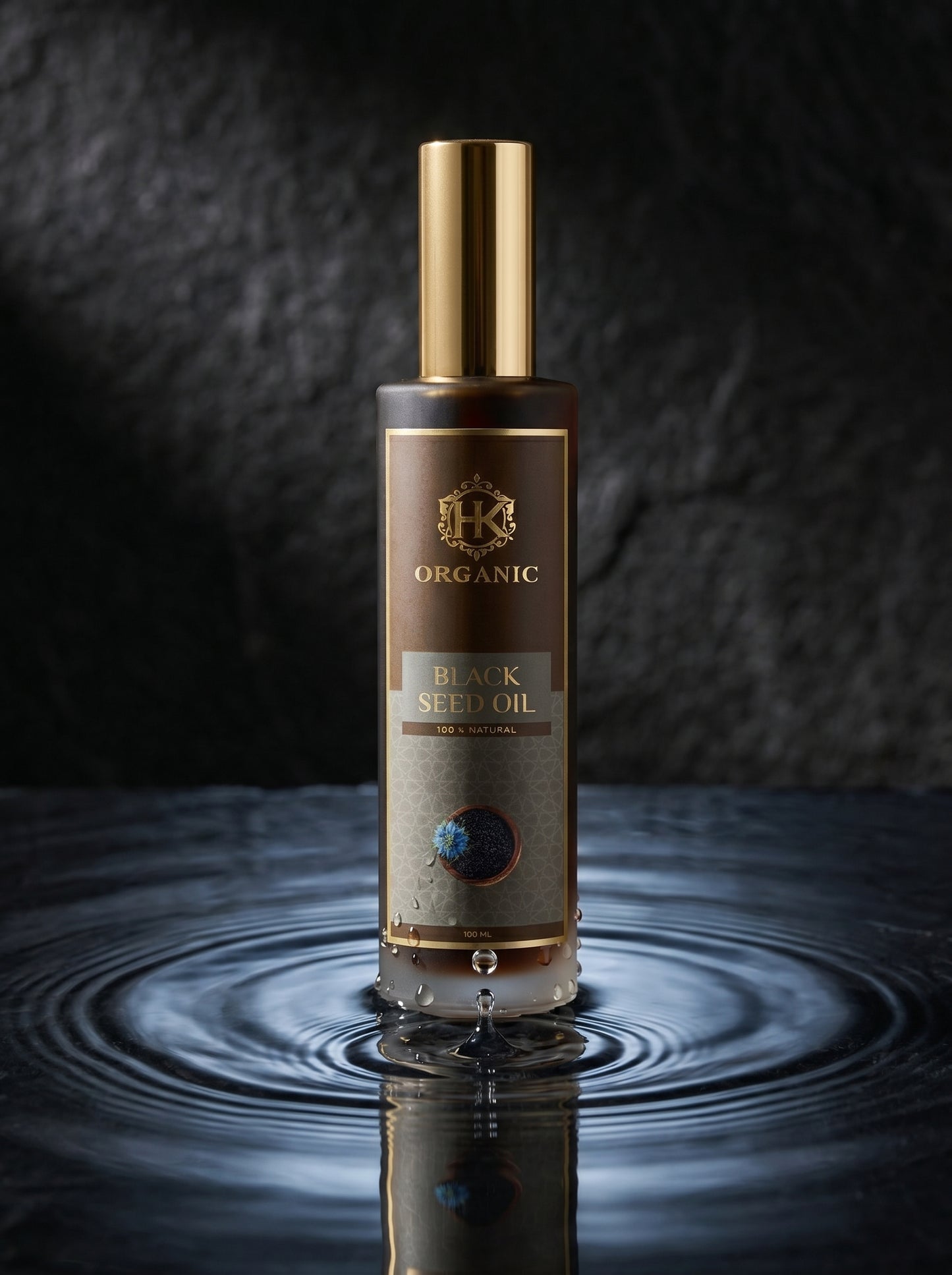 Bottle of organic black seed oil with a gold cap on a reflective surface.