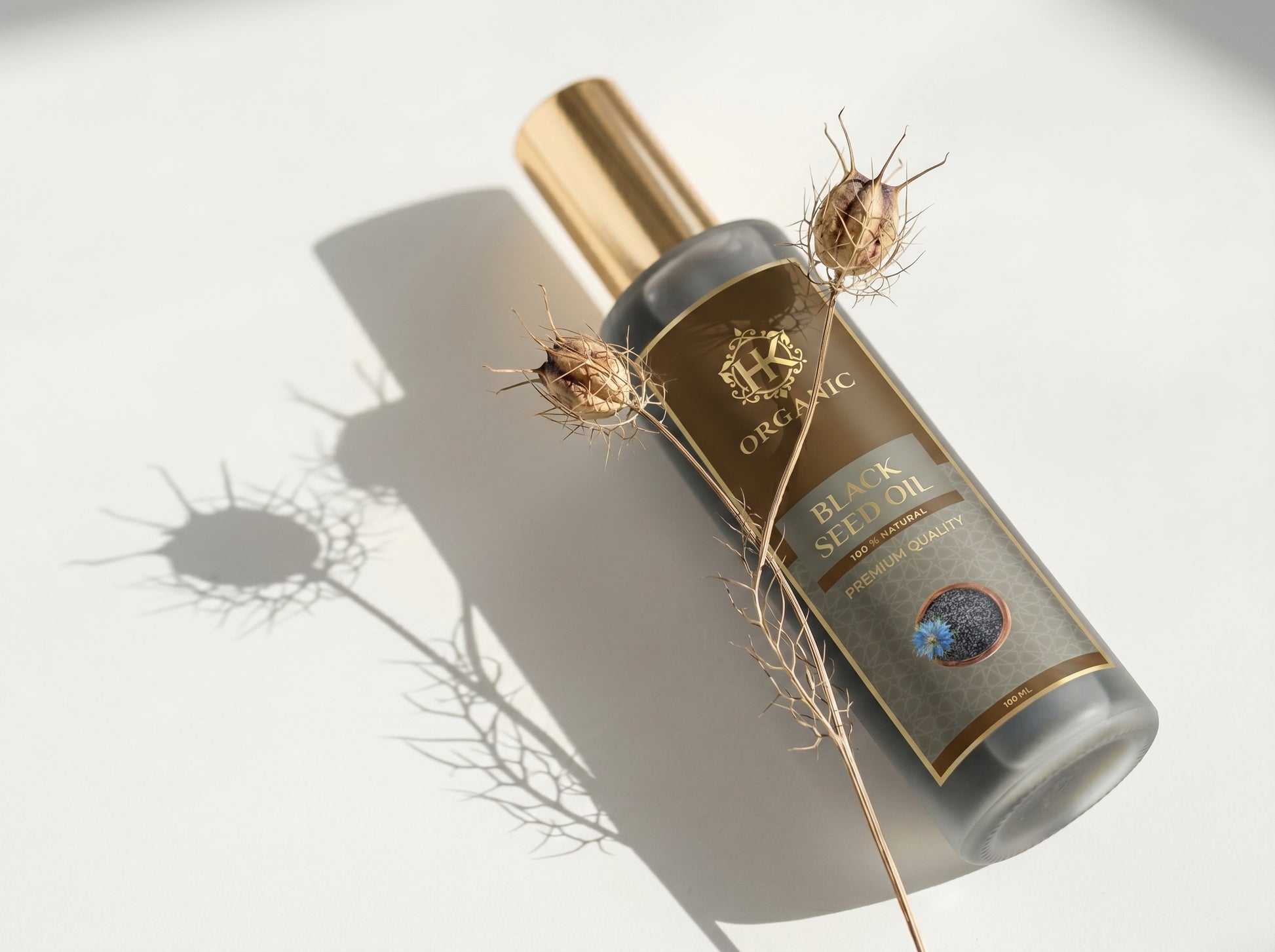 Bottle of organic black seed oil with a gold cap on a light background