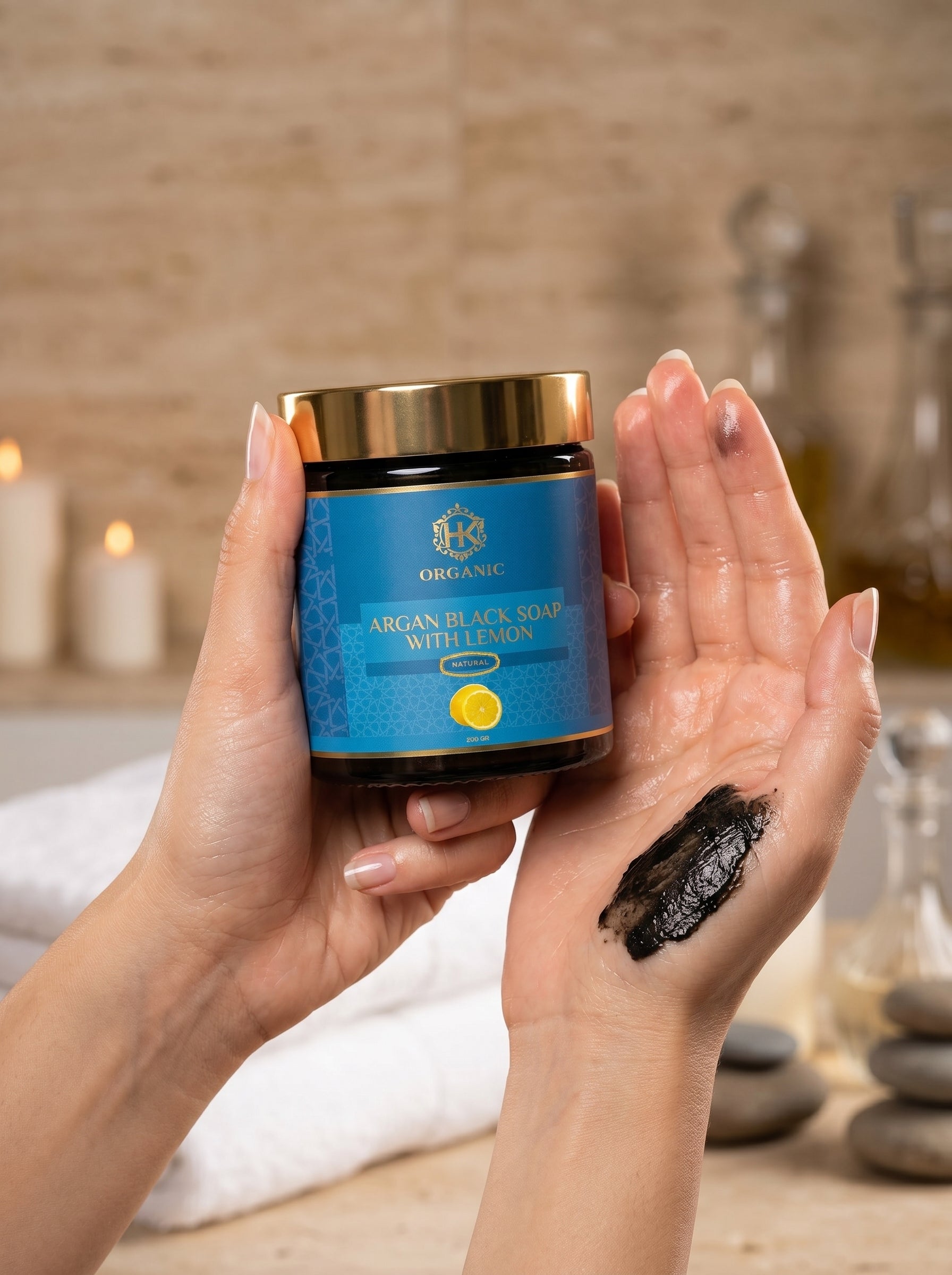 Person holding a jar of Argan Black Soap with a visible black substance on their palm.
