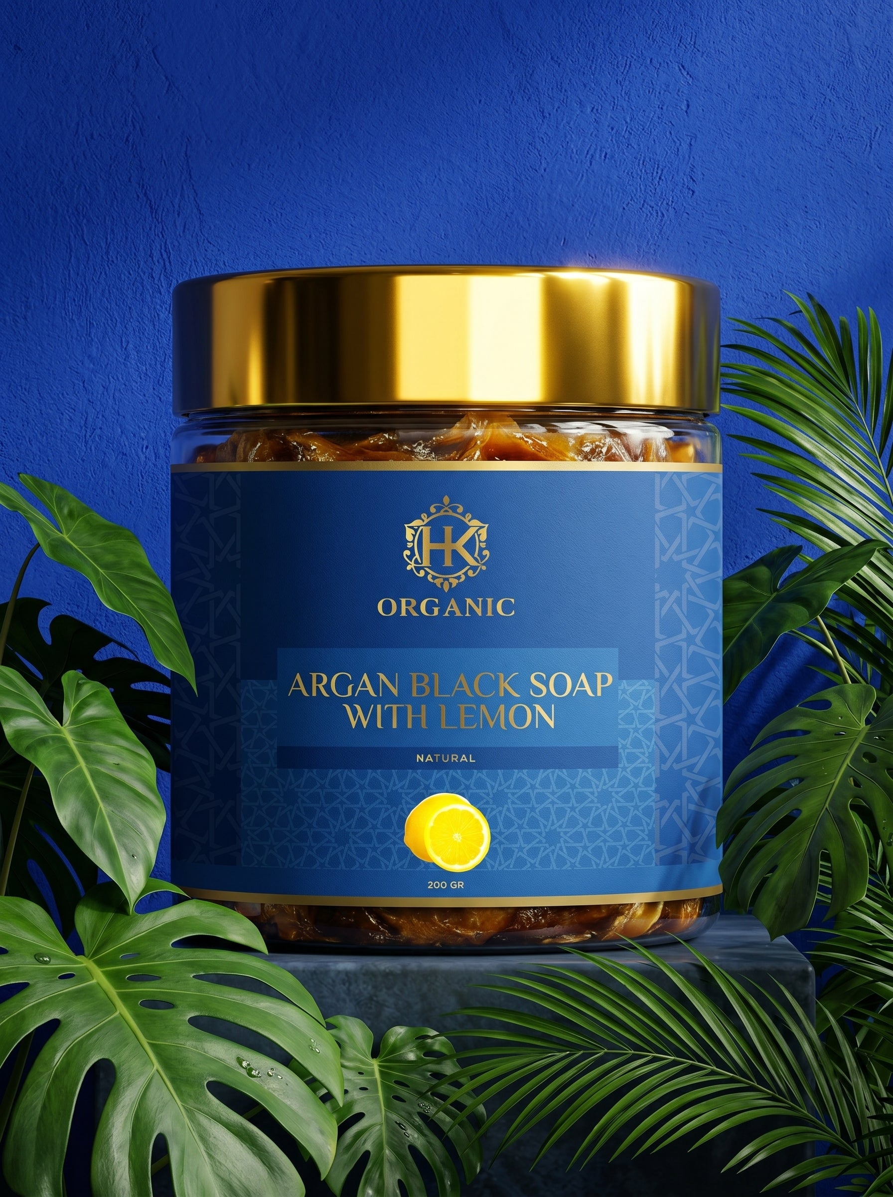 Jar of argan black soap with lemon on a blue background with green leaves.