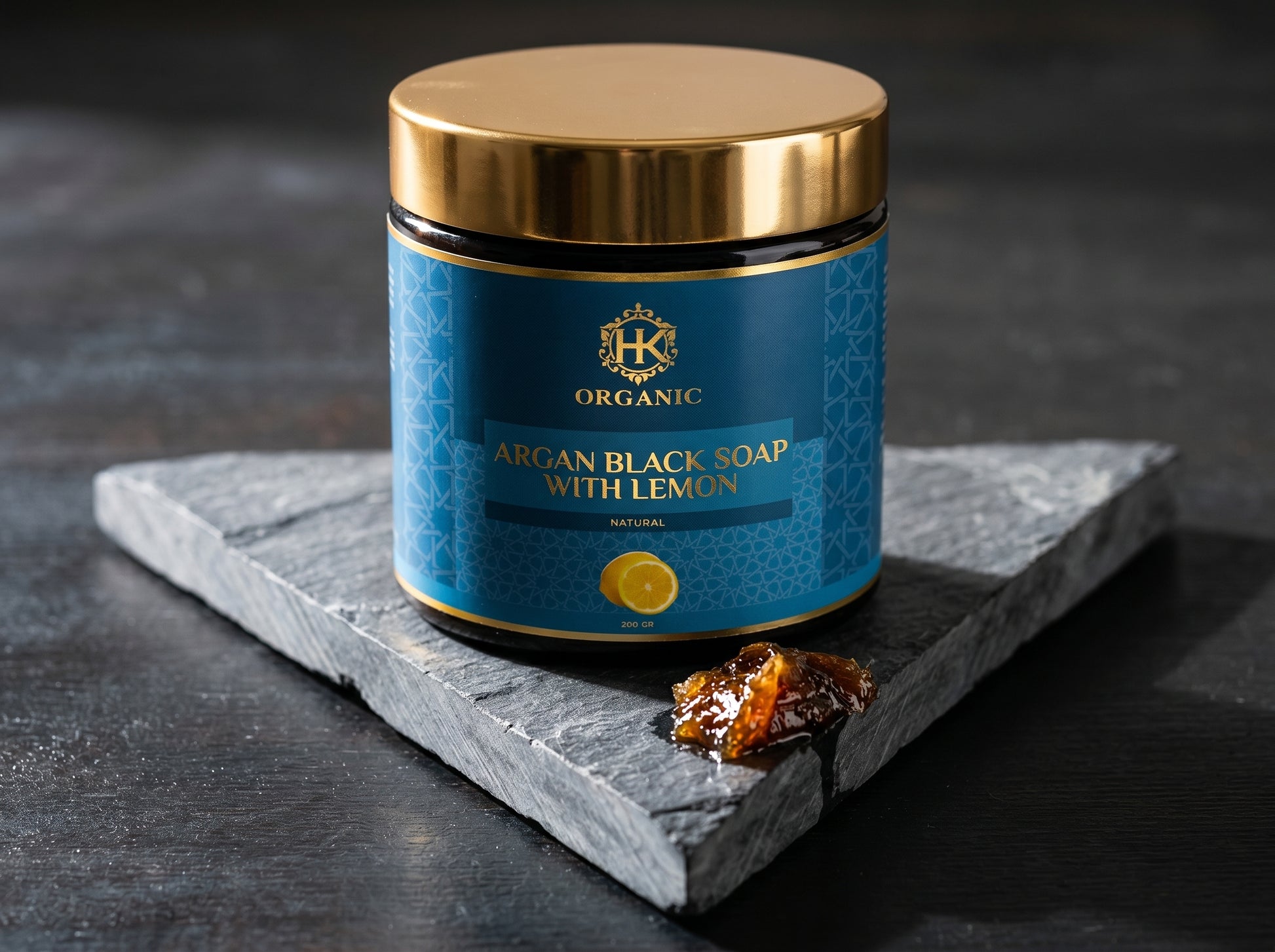 Jar of argan black soap with lemon on a dark surface