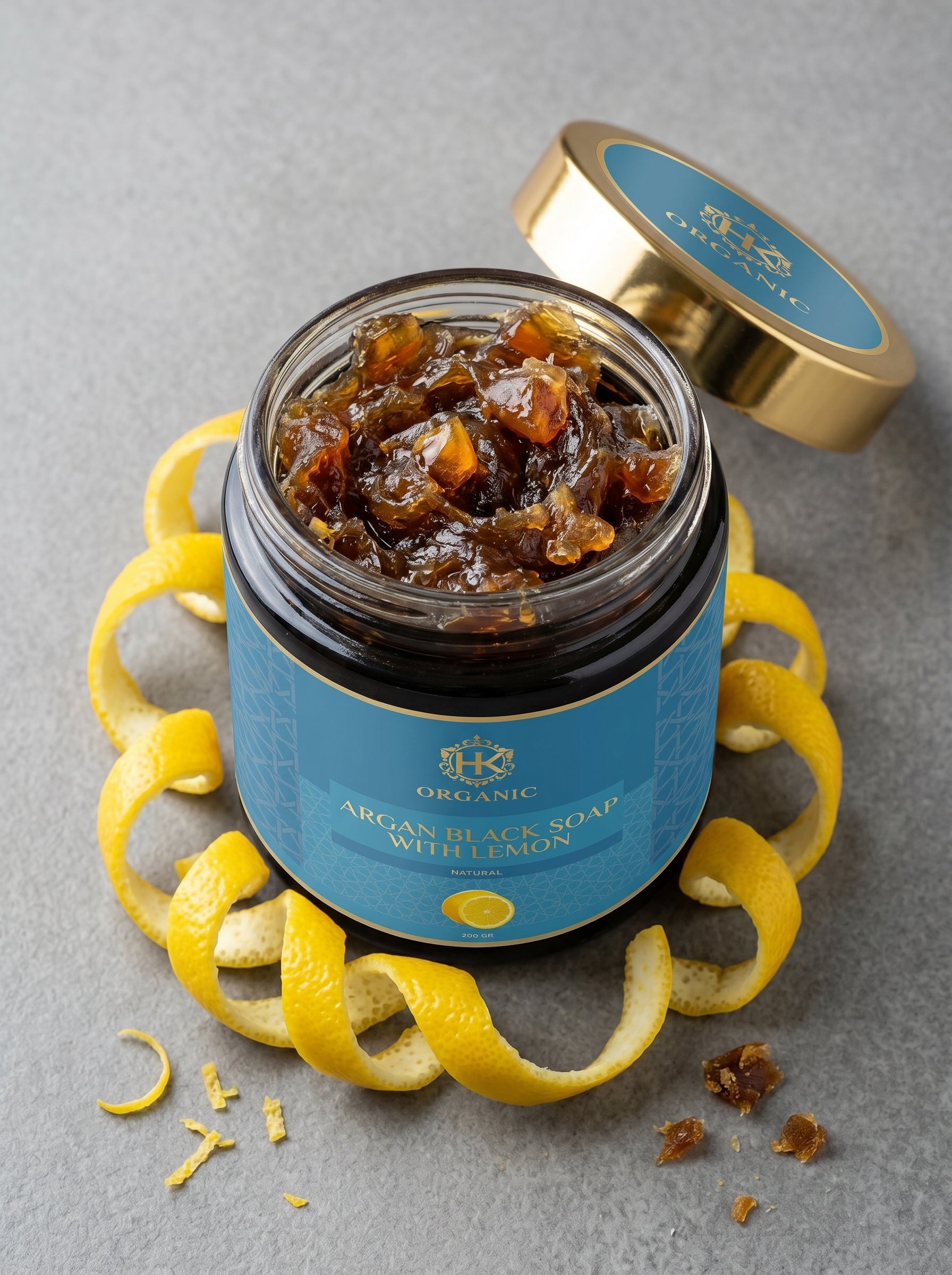 Jar of argan black soap with lemon peels on a gray background