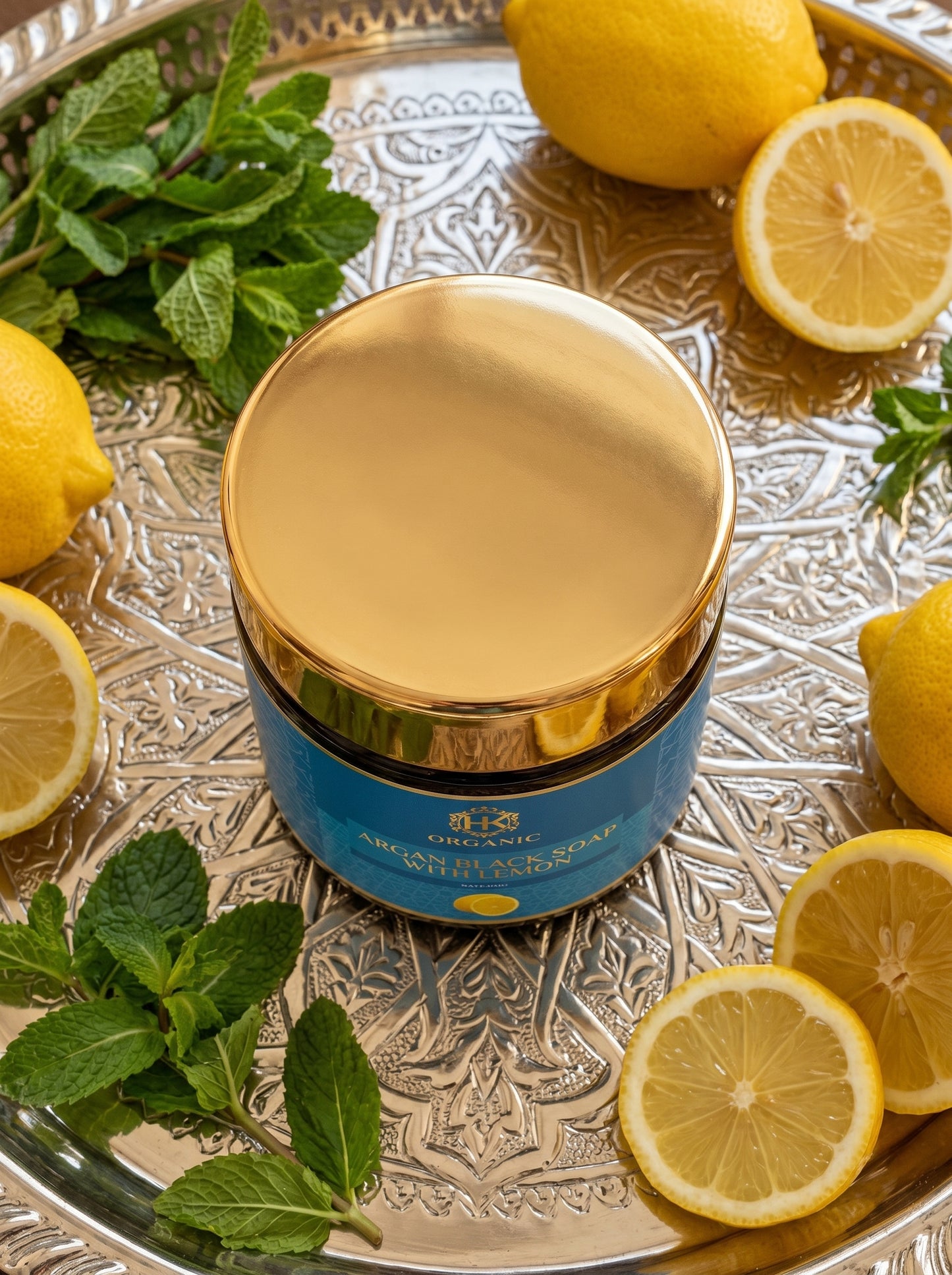 Blue jar with gold lid on a silver tray surrounded by lemons and mint leaves