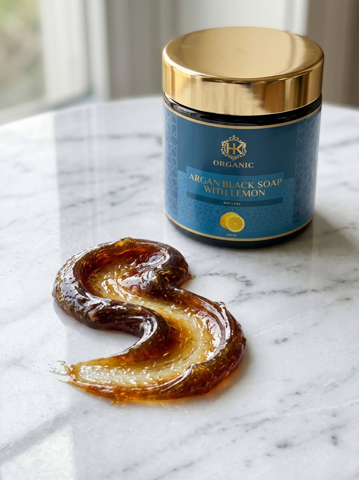 Jar of argan black soap with lemon on a marble surface