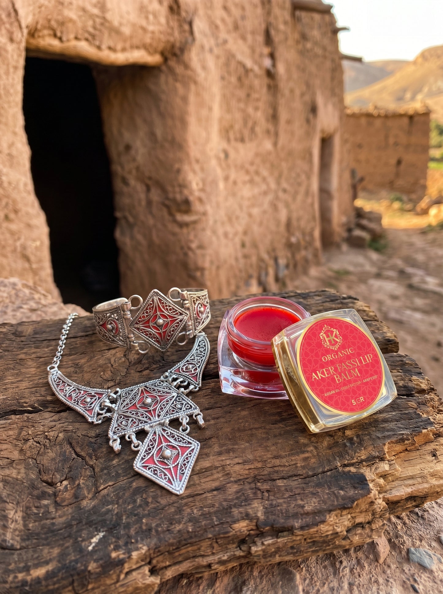 Silver jewelry and red lip balm on a wooden surface with a rustic background