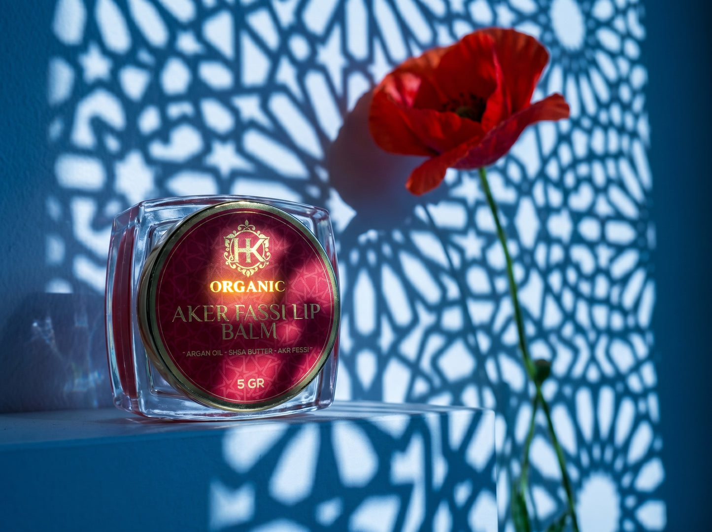 Organic lip balm with a red flower against a textured blue background