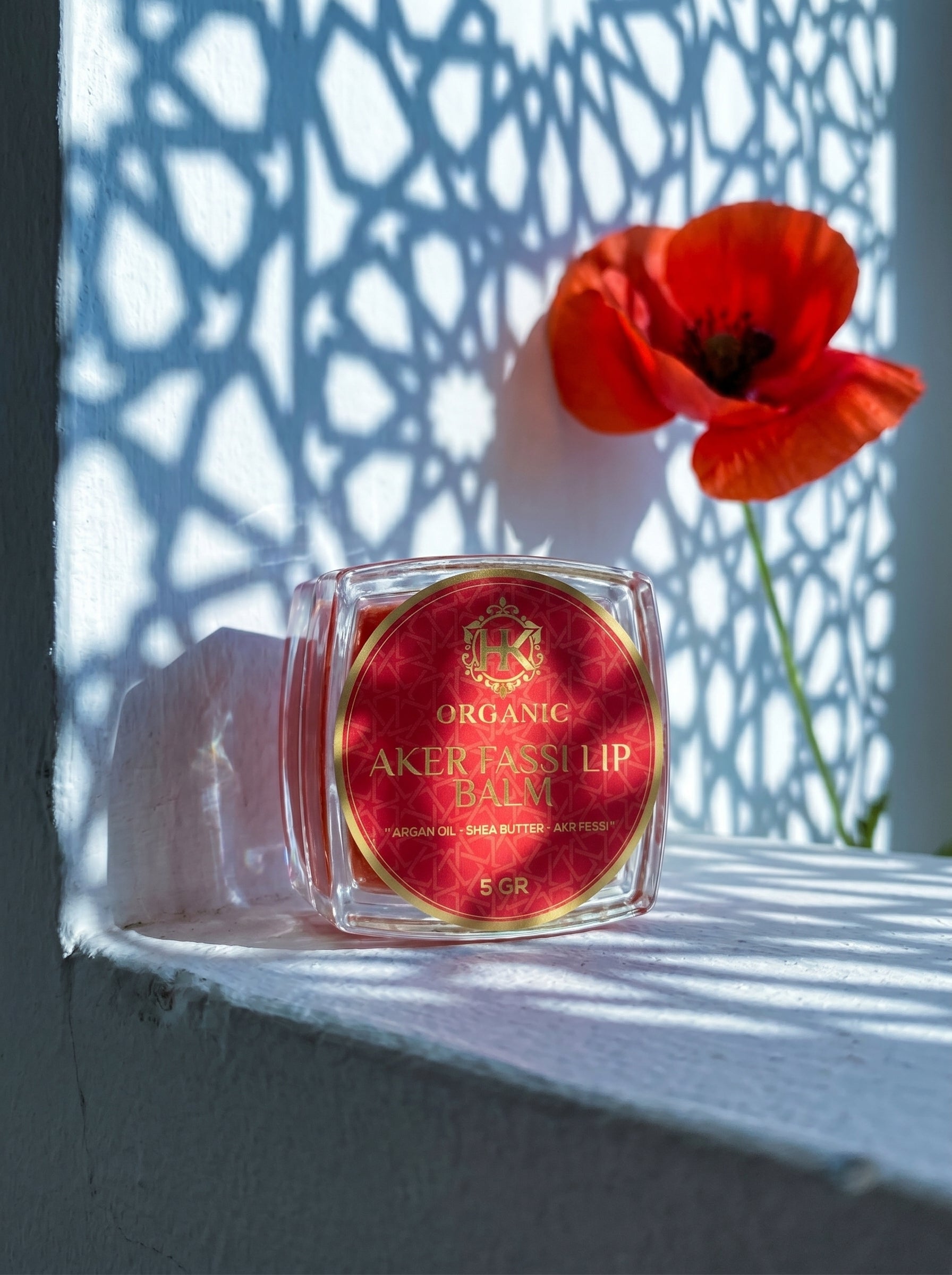 Lip balm with red label on a white surface with a red flower