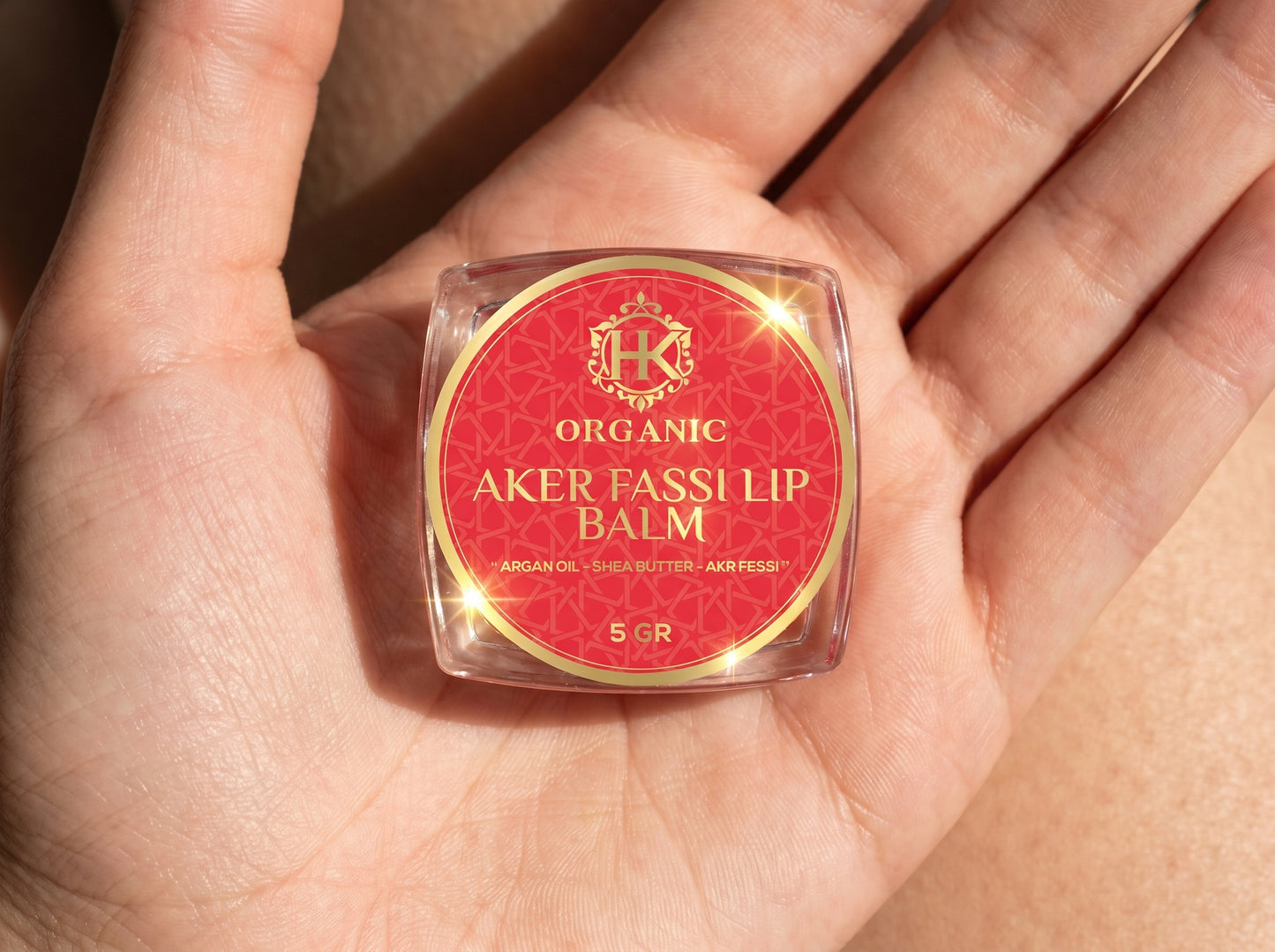 Organic Aker Fassi lip balm held in a hand with a visible brand logo.