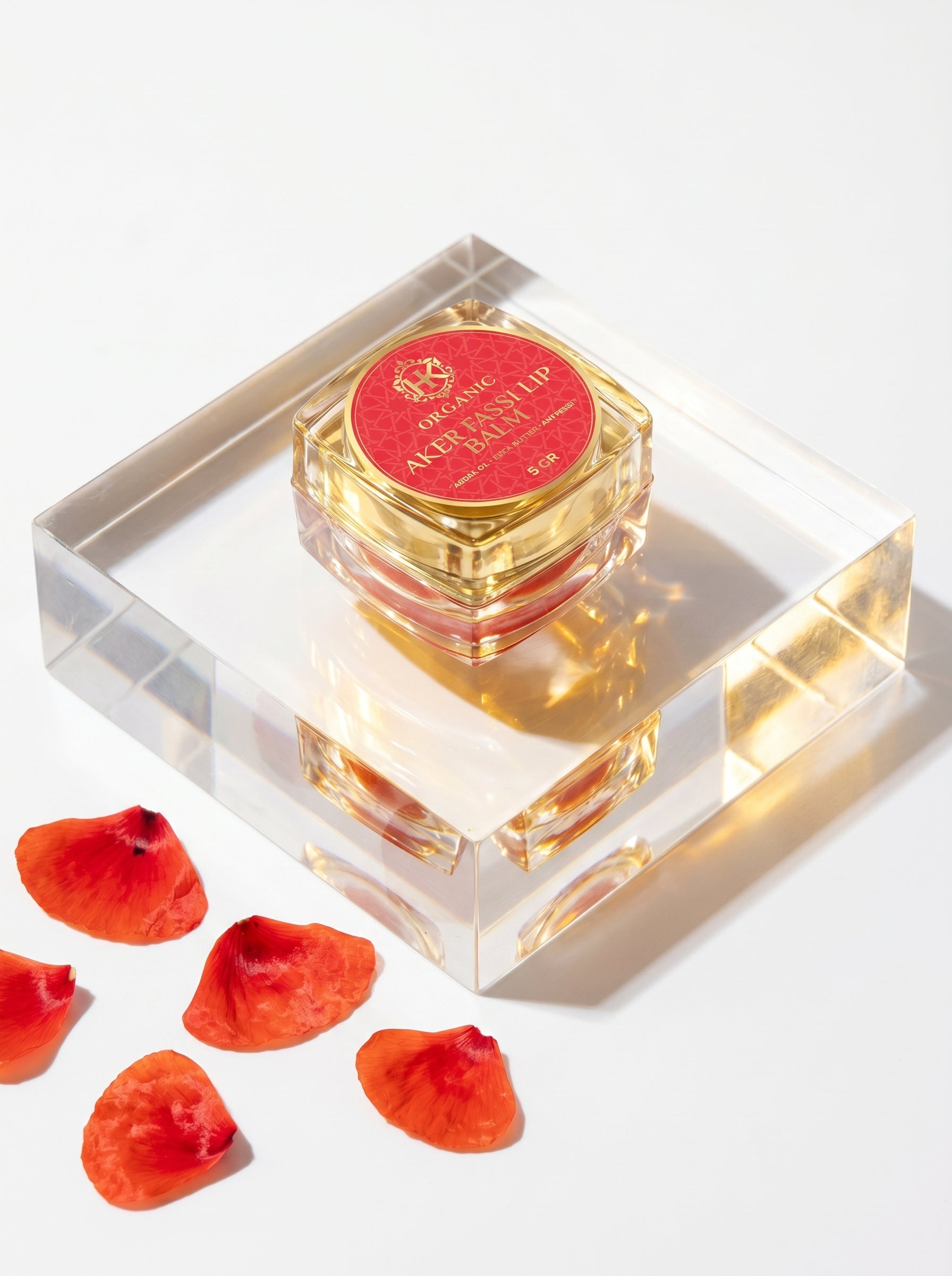 Perfume bottle with red cap and petals on a white background