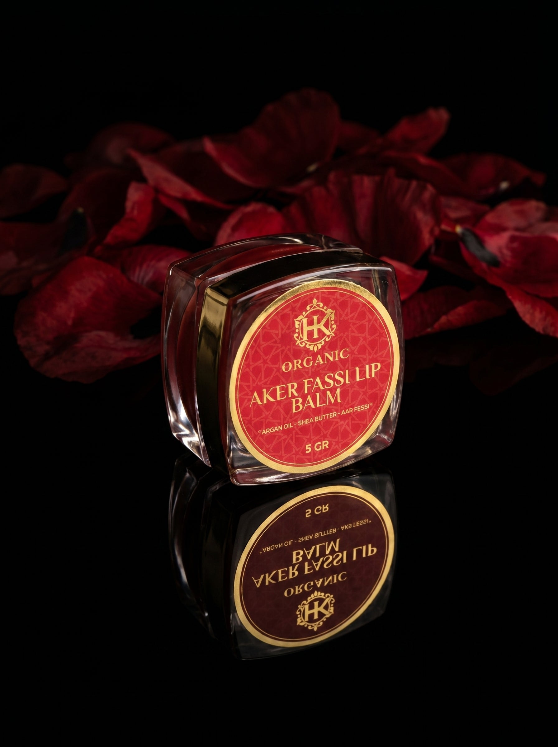Lip balm with red and gold packaging on a dark background