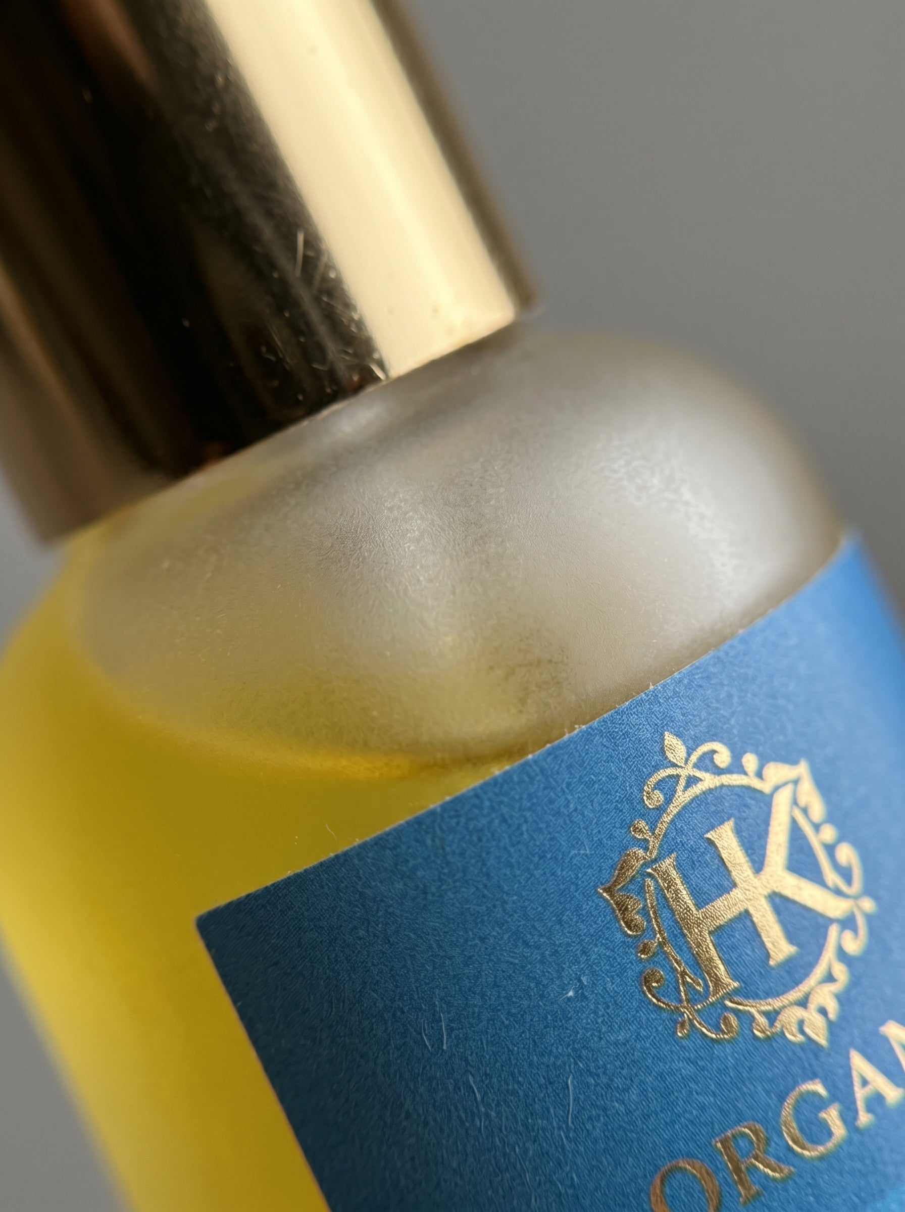 Close-up of a bottle with a blue label and gold cap, featuring a logo.