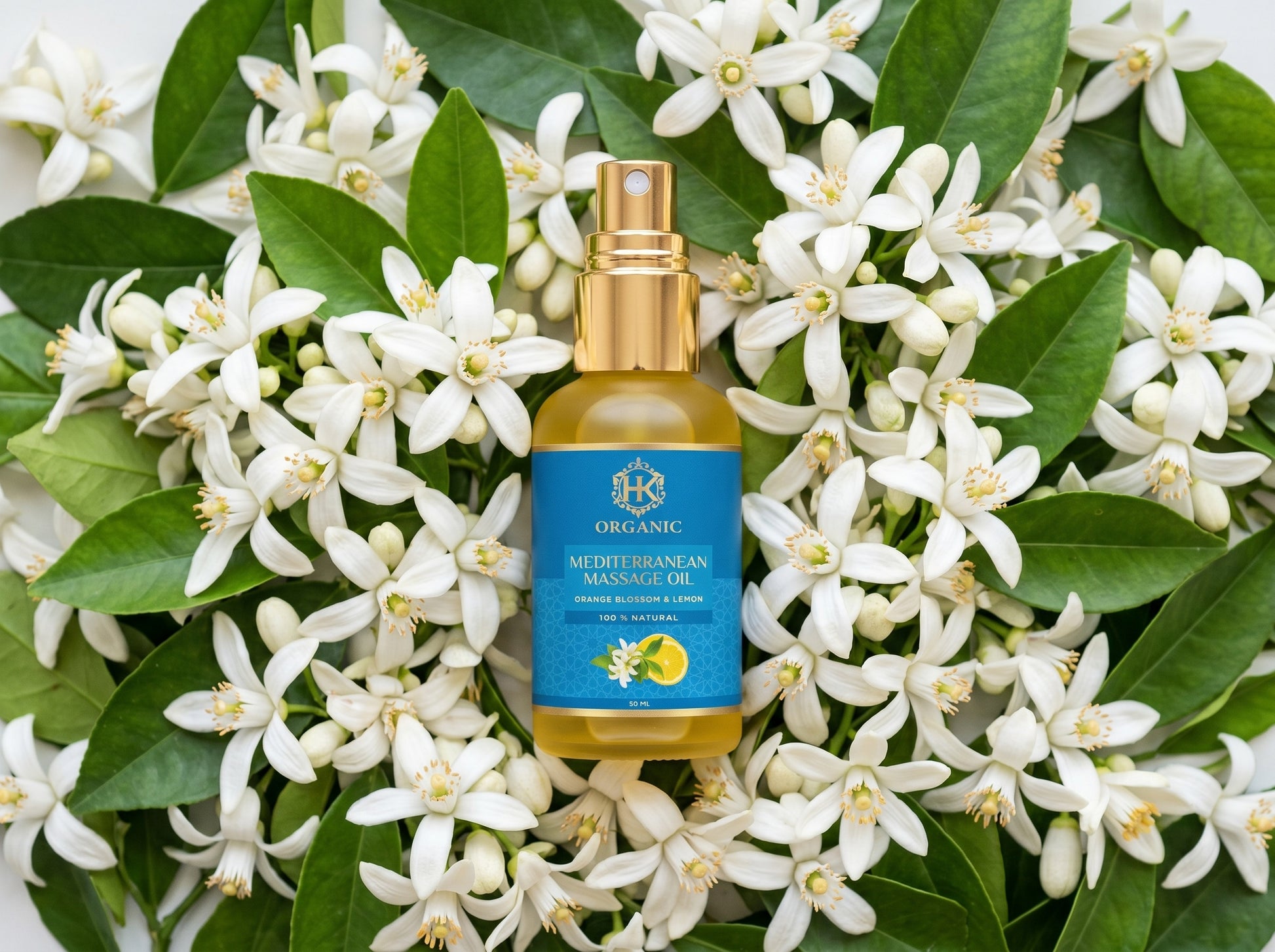 Bottle of organic Mediterranean mango oil surrounded by white flowers and green leaves