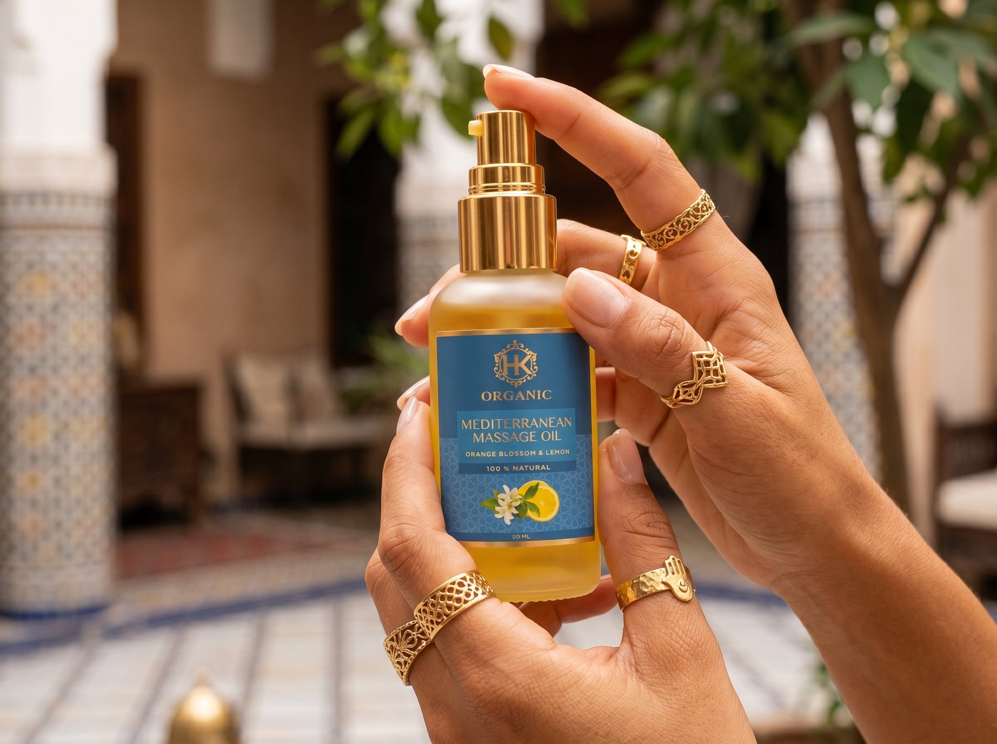 Hand holding a bottle of organic massage oil with a decorative background