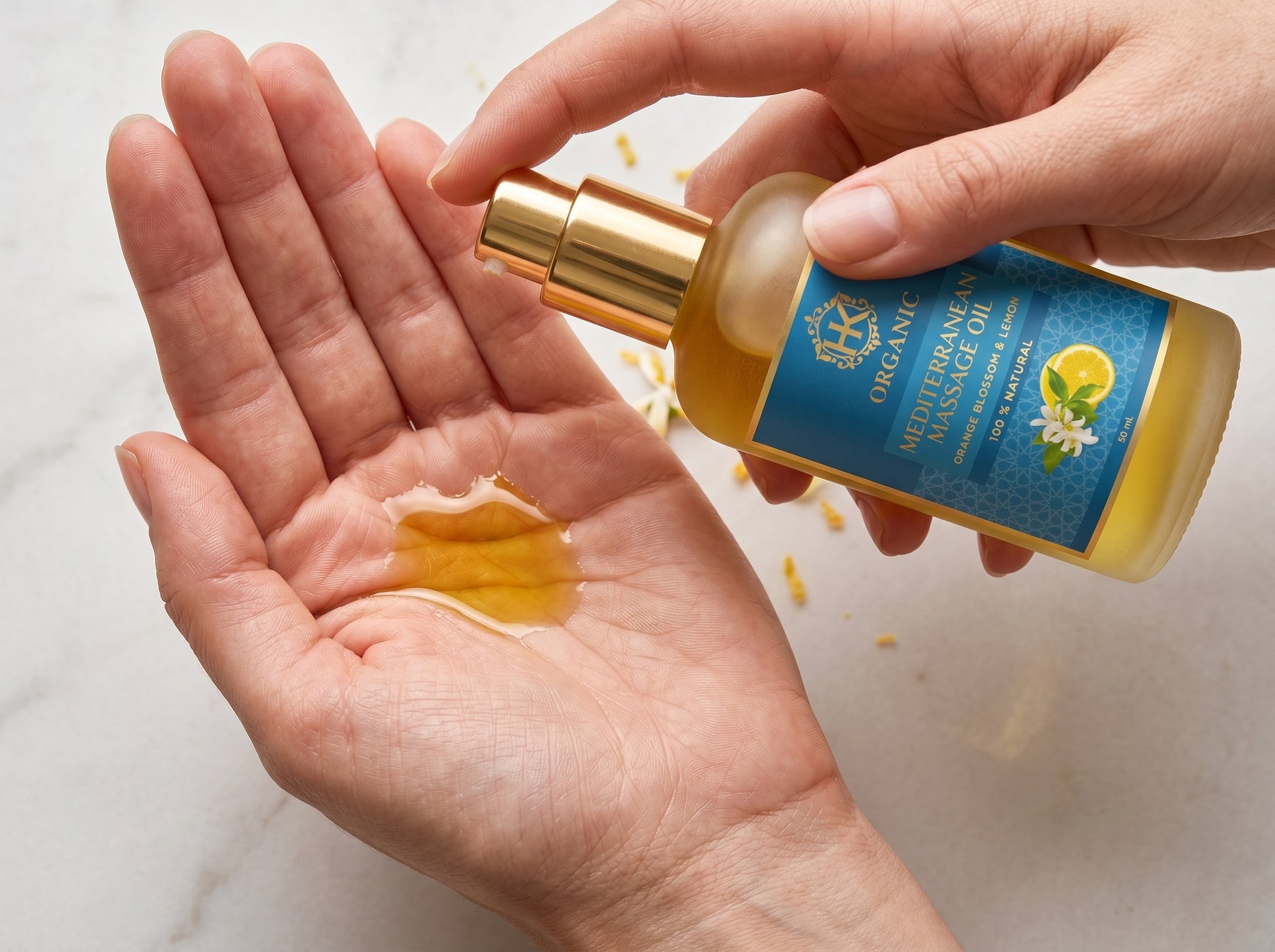 Hand holding a bottle of massage oil with a visible label on a light background