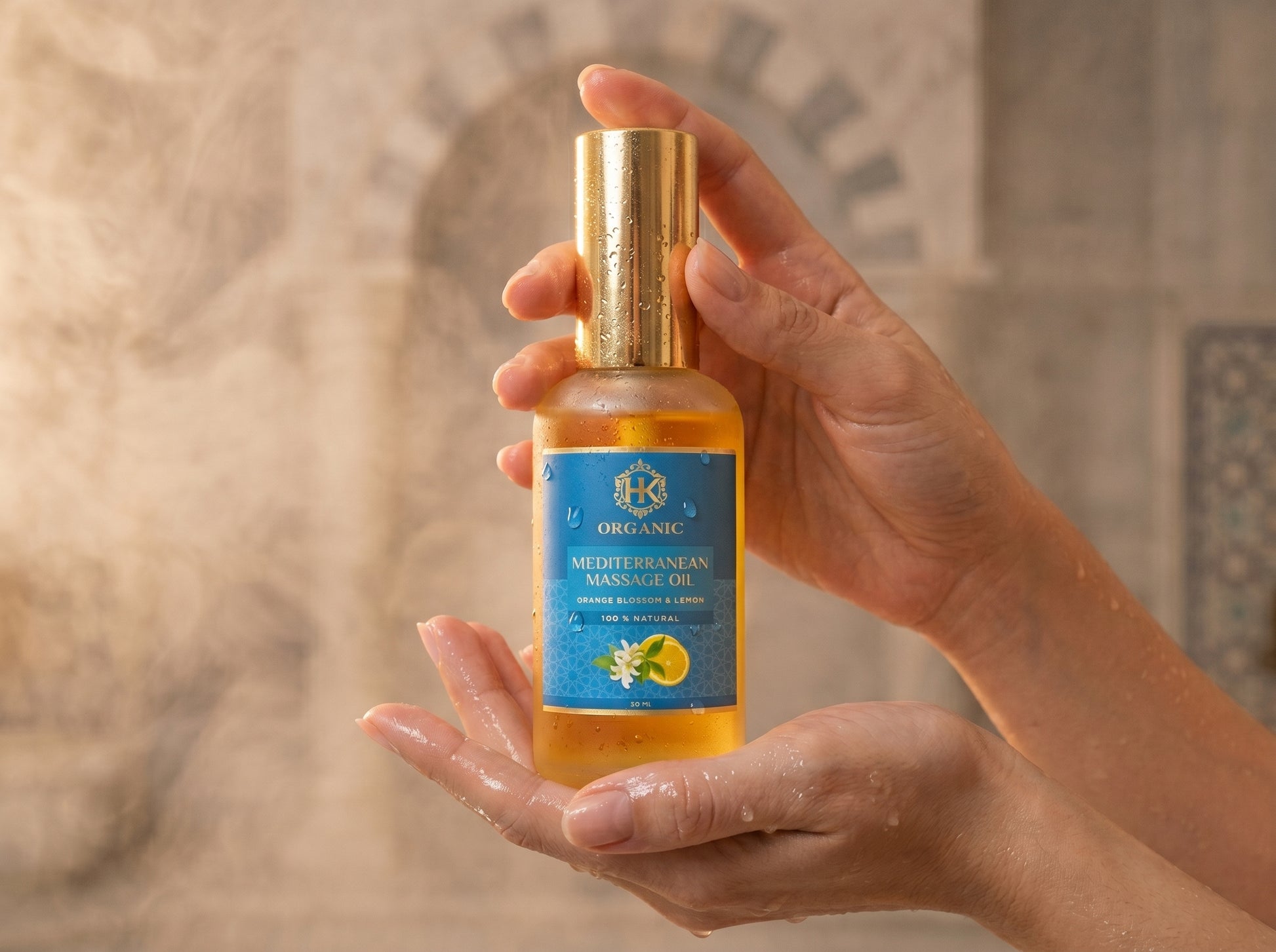 Hand holding a bottle of organic mertle orange massage oil with a decorative background