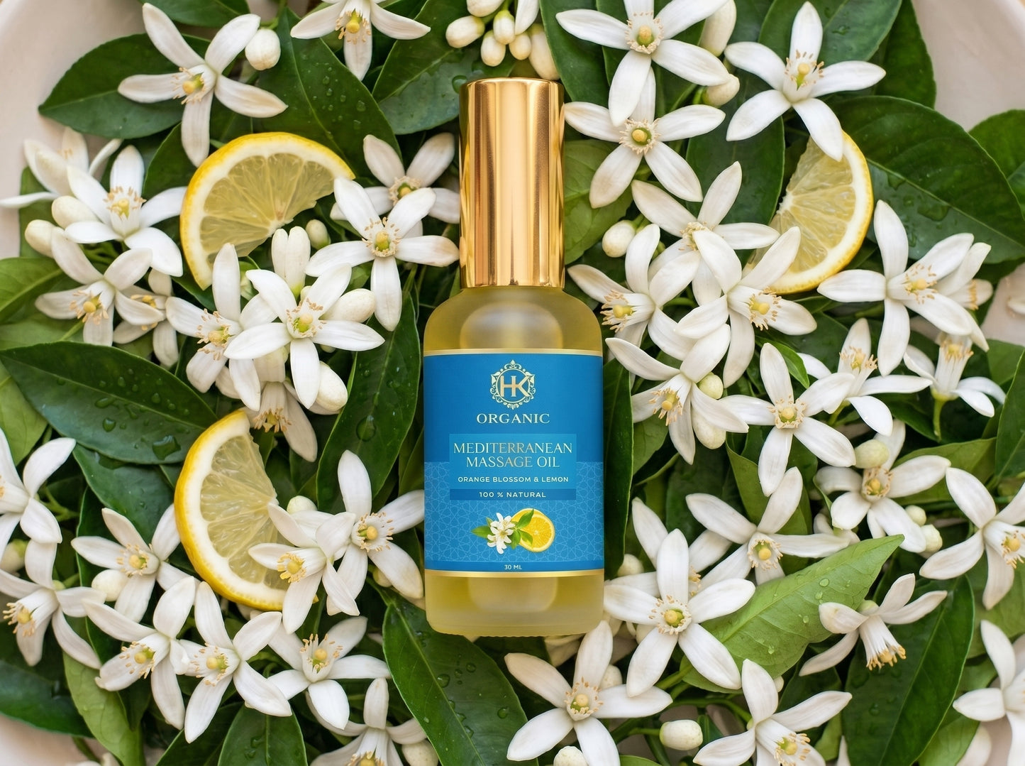 Bottle of Mediterranean Manzanilla organic oil surrounded by white flowers and lemon slices on a white background